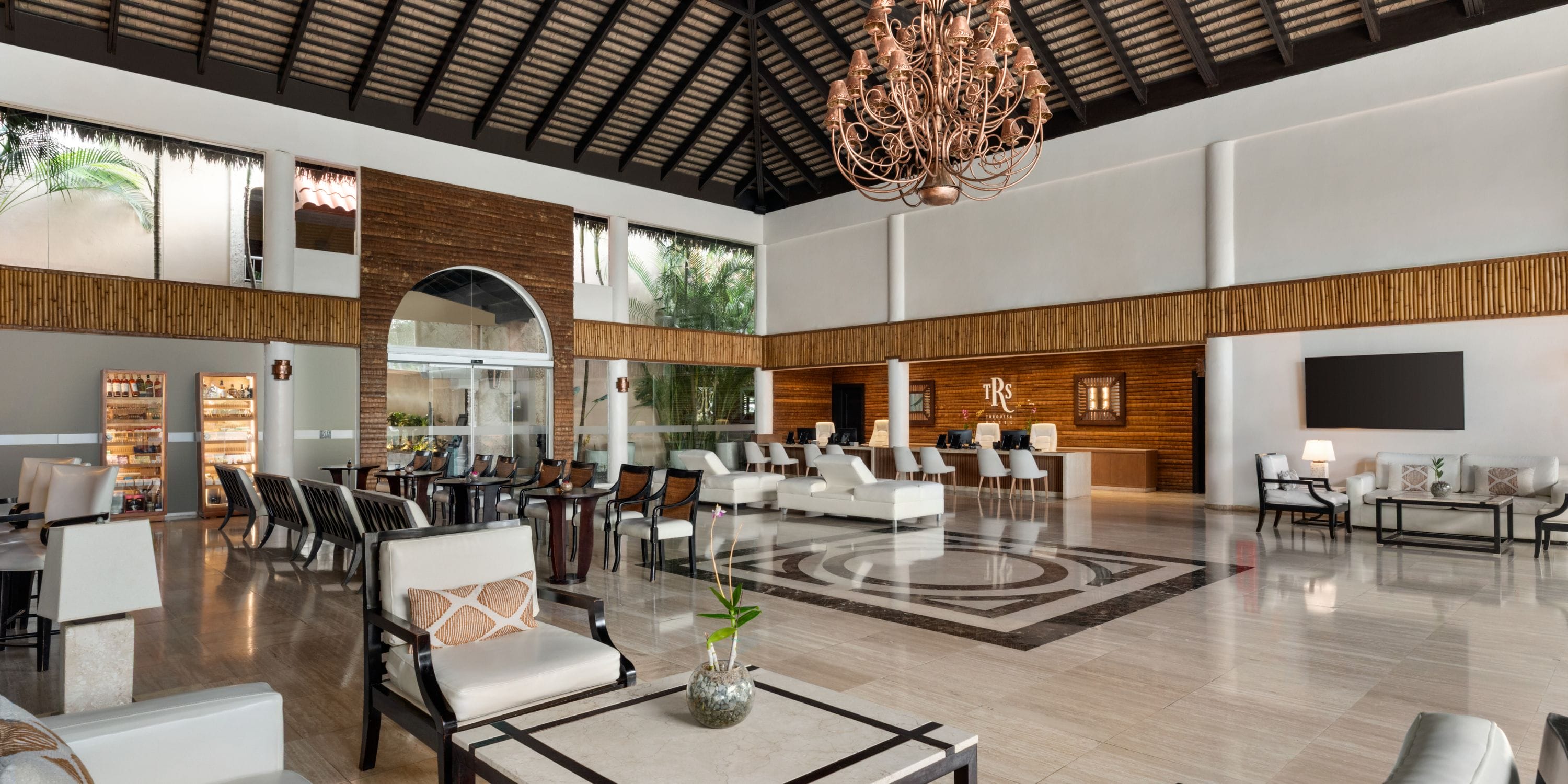 Spacious TRS Turquesa lobby, ideal for destination weddings, with modern seating and grand chandelier.