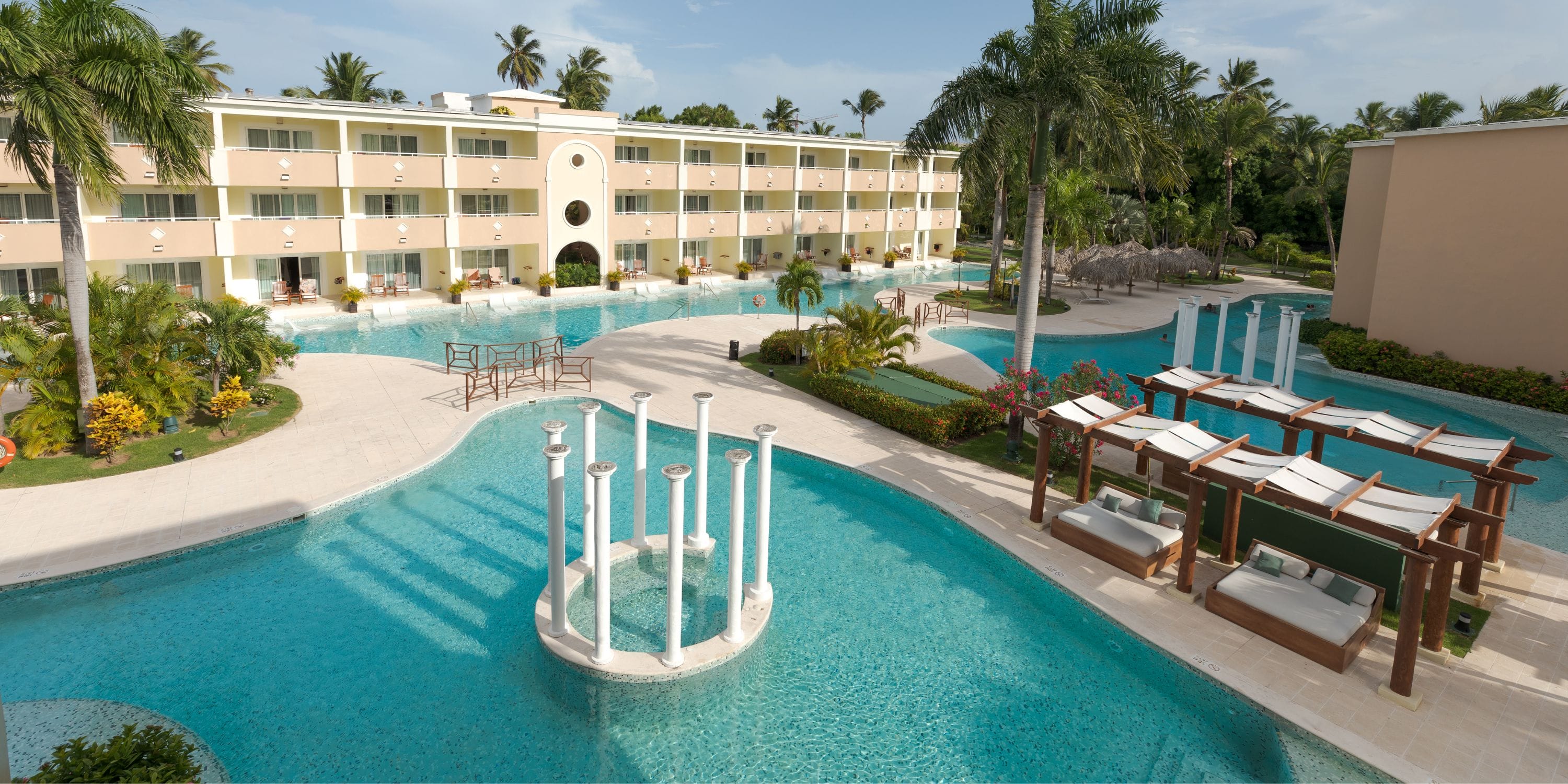 TRS Turquesa: Modern resort ideal for a destination wedding, with a large pool, lounge chairs, and palms.