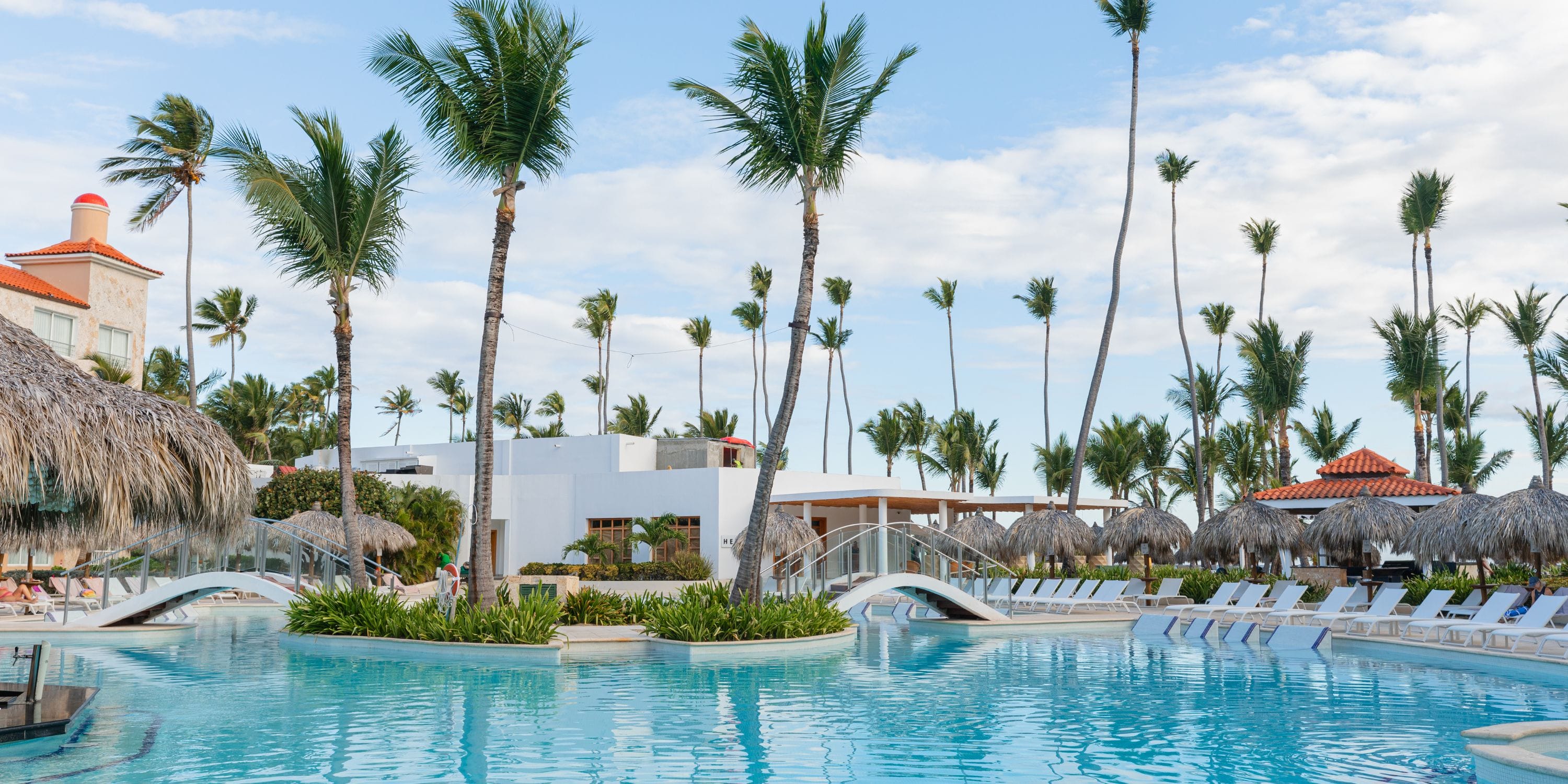 TRS Turquesa: ideal destination wedding venue with a large pool, palm trees, bridges, and resort buildings.