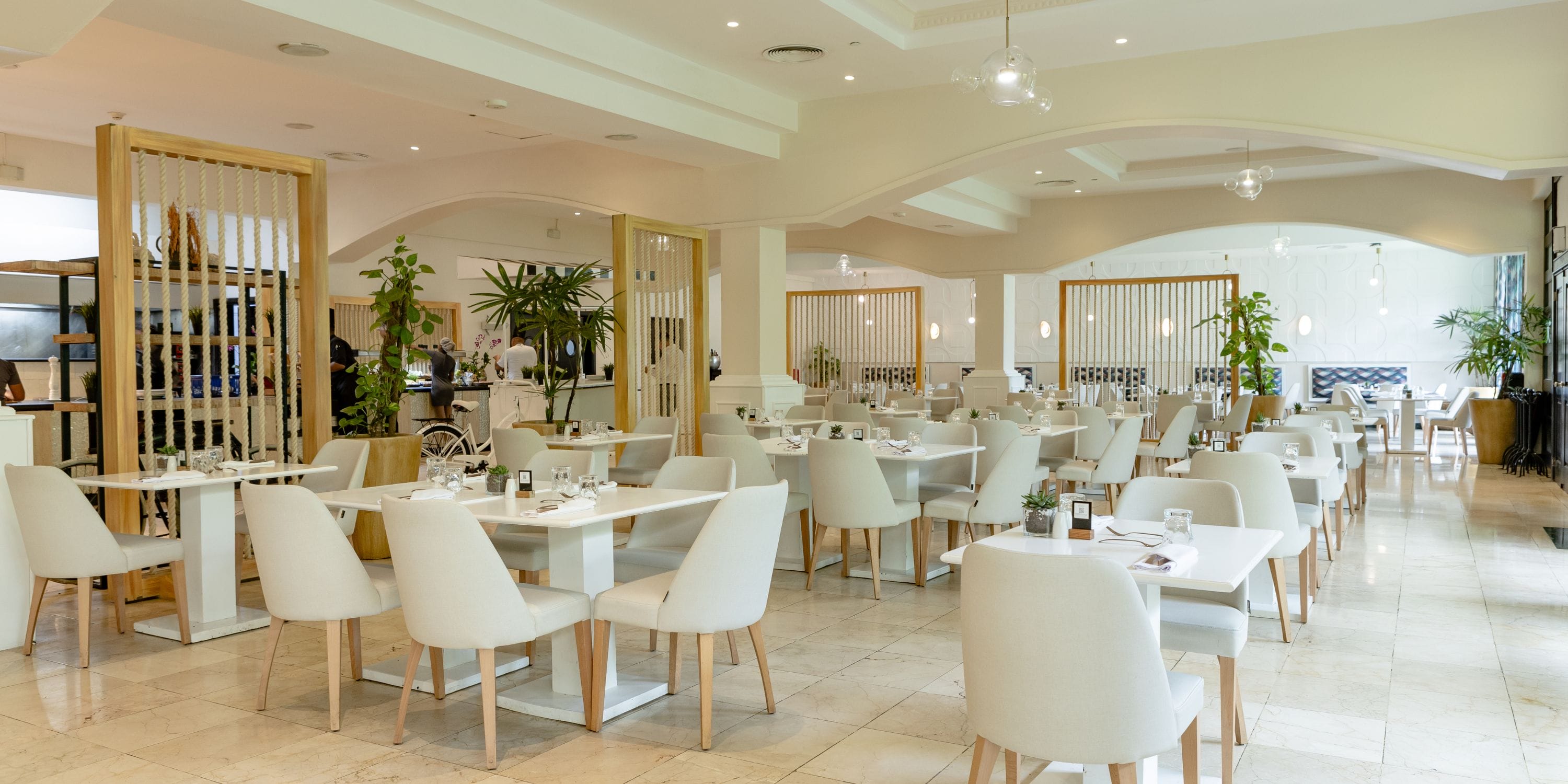 TRS Turquesa: modern wedding venue with white tables, dining chairs, and lush greenery&mdash;ideal for a destination wedding.