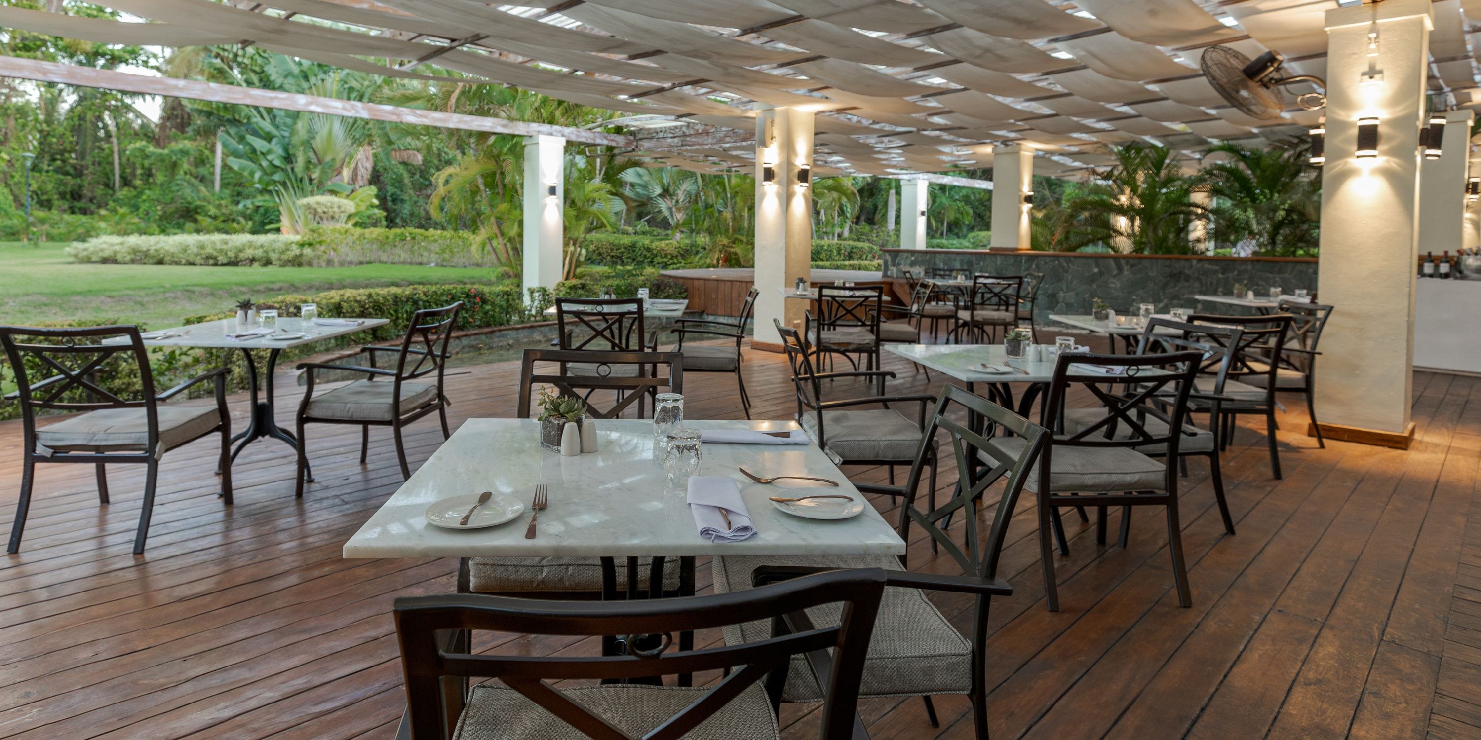 TRS Turquesa outdoor patio set for a destination wedding, empty tables and chairs amid lush greenery.