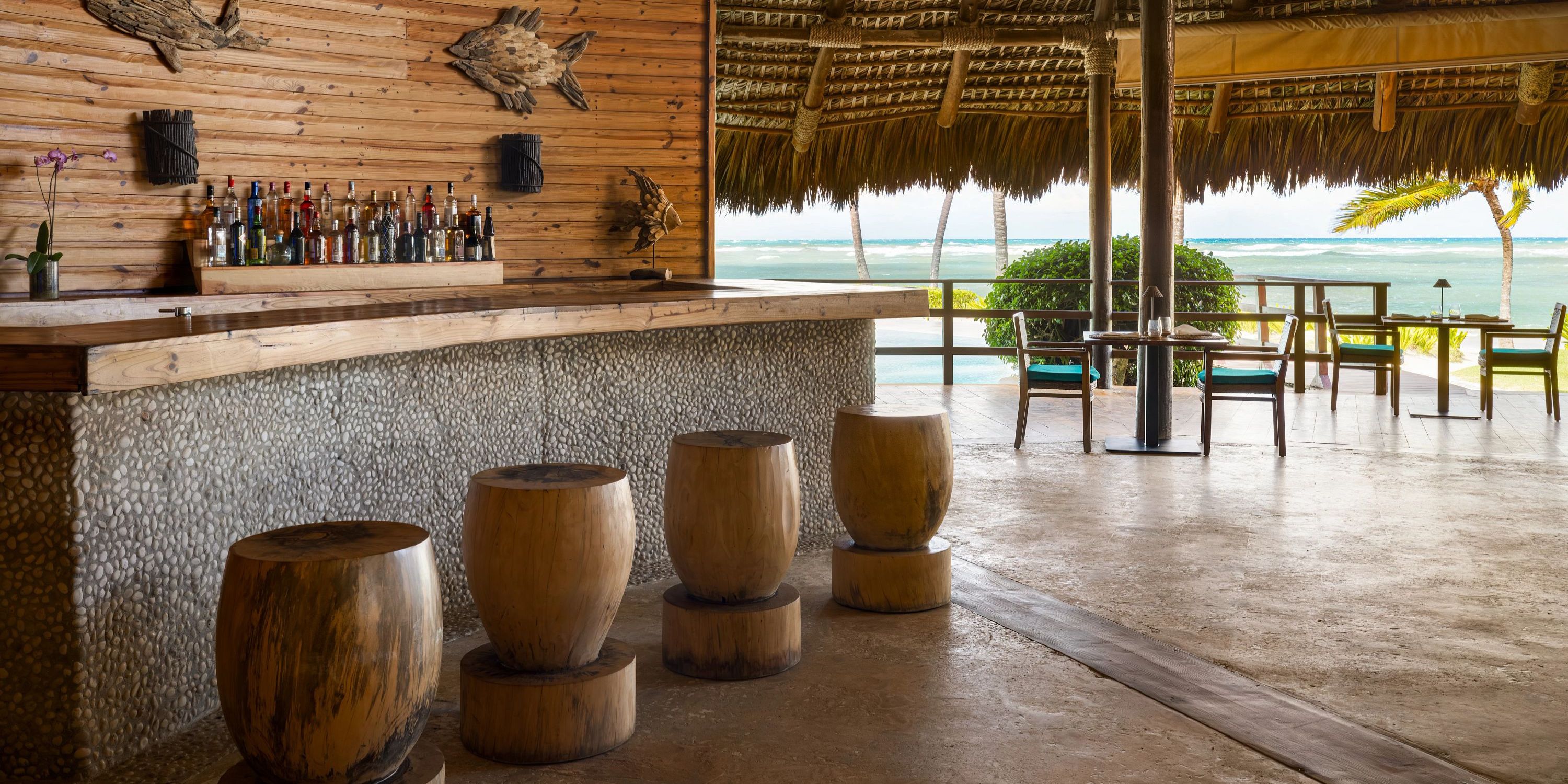 Zoetry Agua Punta Cana: outdoor tropical bar with wooden stools and ocean view, ideal for weddings.