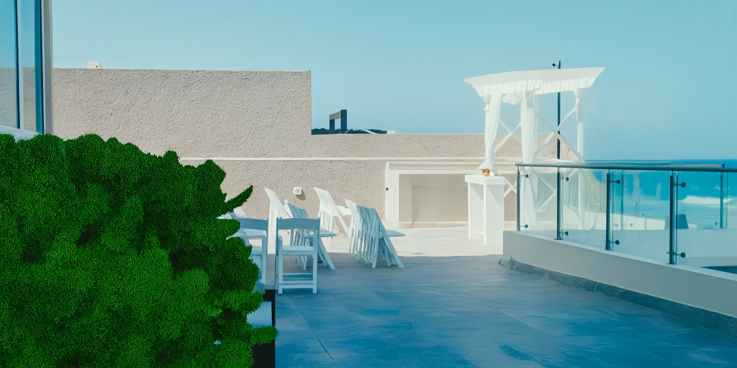 Experience the Hard Rock Cancun's rooftop patio, featuring white chairs and tables, glass railing, and breathtaking ocean views on a sunny day.