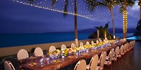 The Krystal Grand Nuevo Vallarta features an outdoor dining setup adorned with flowers and lights, overlooking a tranquil ocean at dusk.