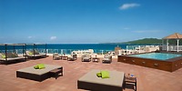 Experience the rooftop terrace at Krystal Grand Nuevo Vallarta, complete with lounge chairs, tables, and a pool that overlooks a scenic ocean view beneath a clear blue sky.