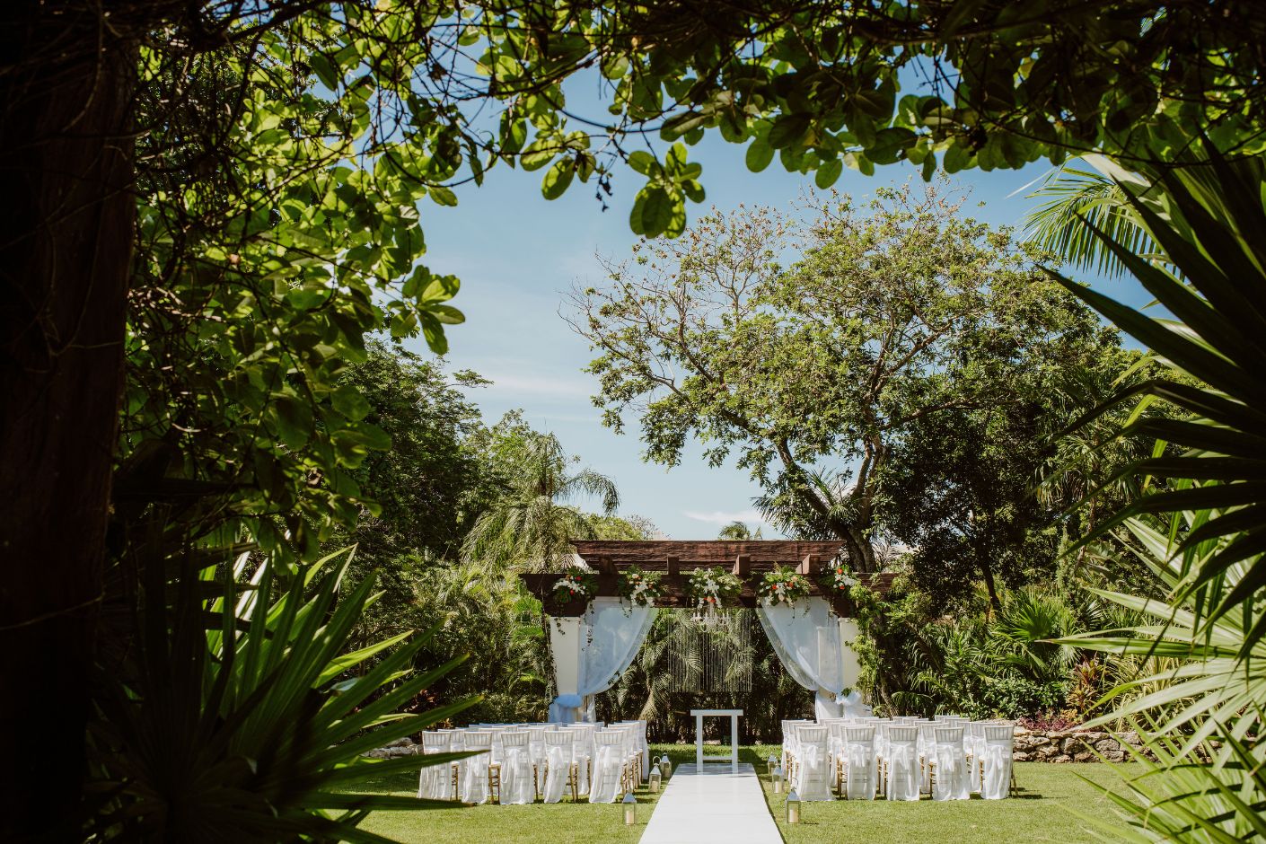 A Sandos Playacar wedding ceremony set up in a tropical garden.