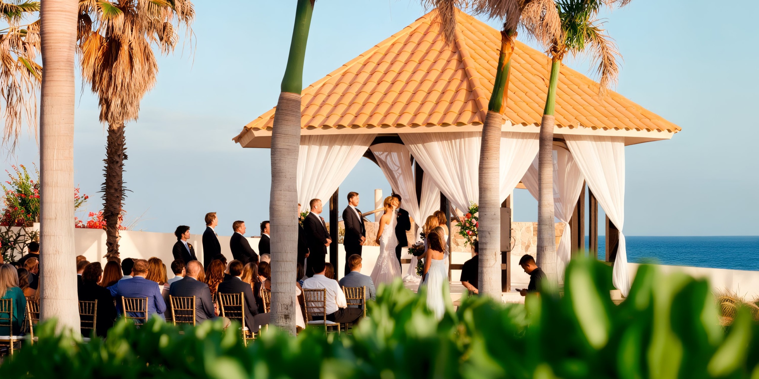 An outdoor wedding ceremony by the ocean at Secrets Puerto Los Cabos, featuring a couple under a canopy, surrounded by the wedding party and guests seated in rows.