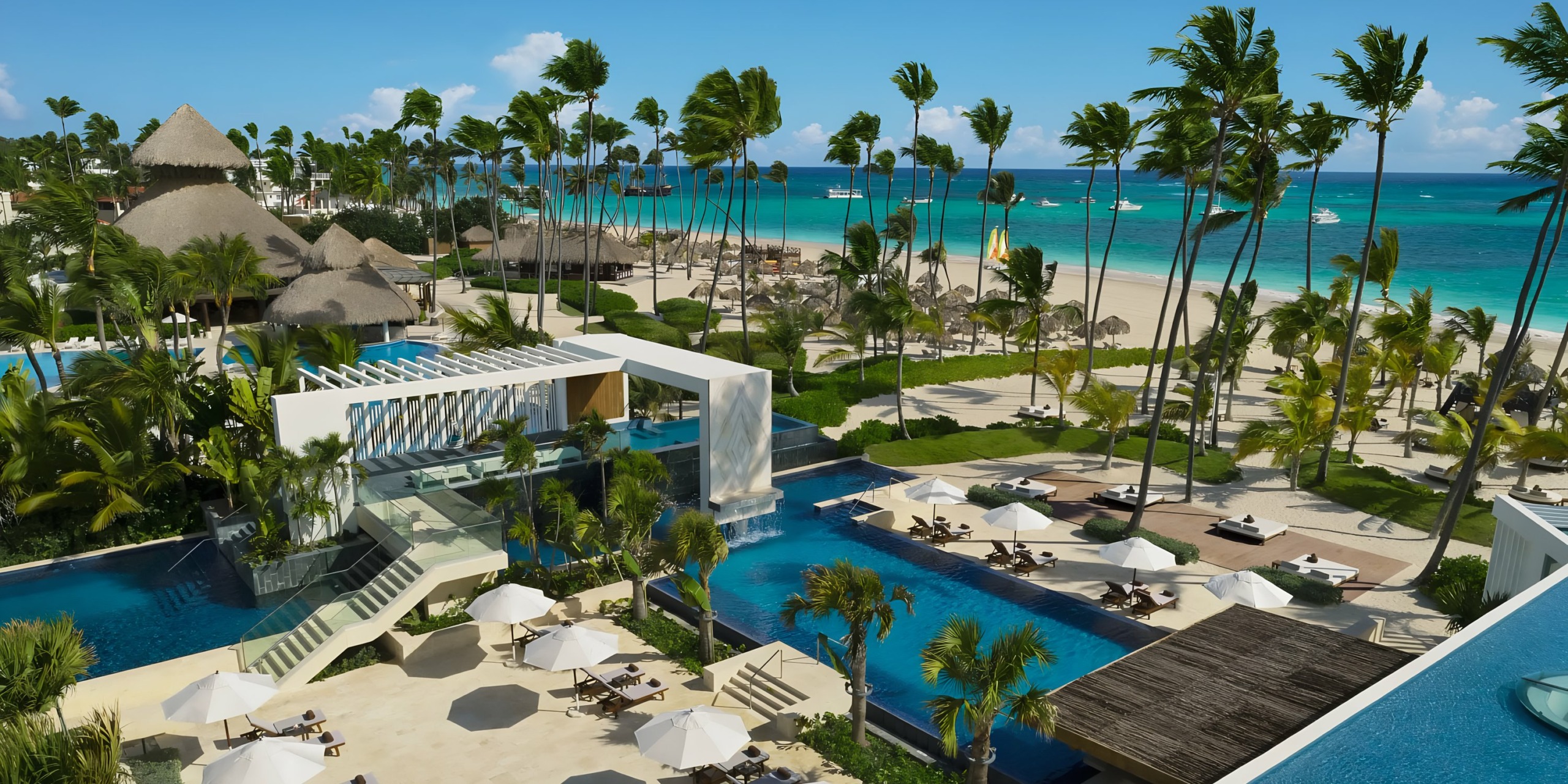 Secrets Royal Beach destination wedding resort with swimming pools, palm trees, and ocean view.