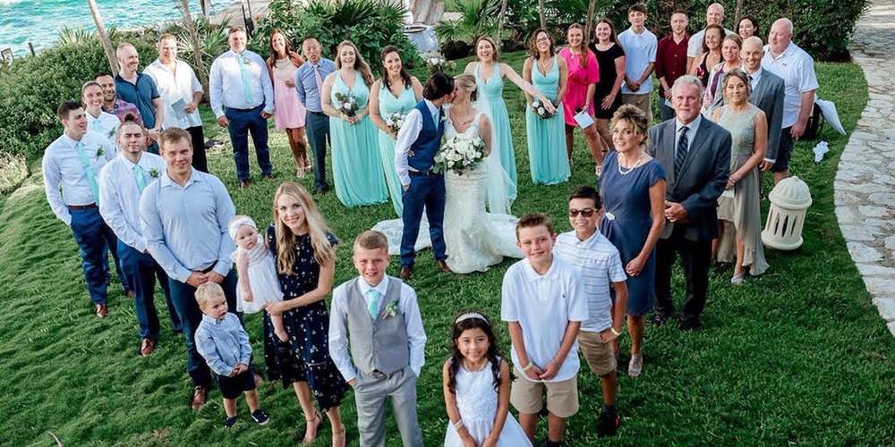 Tiana and Jessica pose with their wedding party and all their guests in the form of a heart