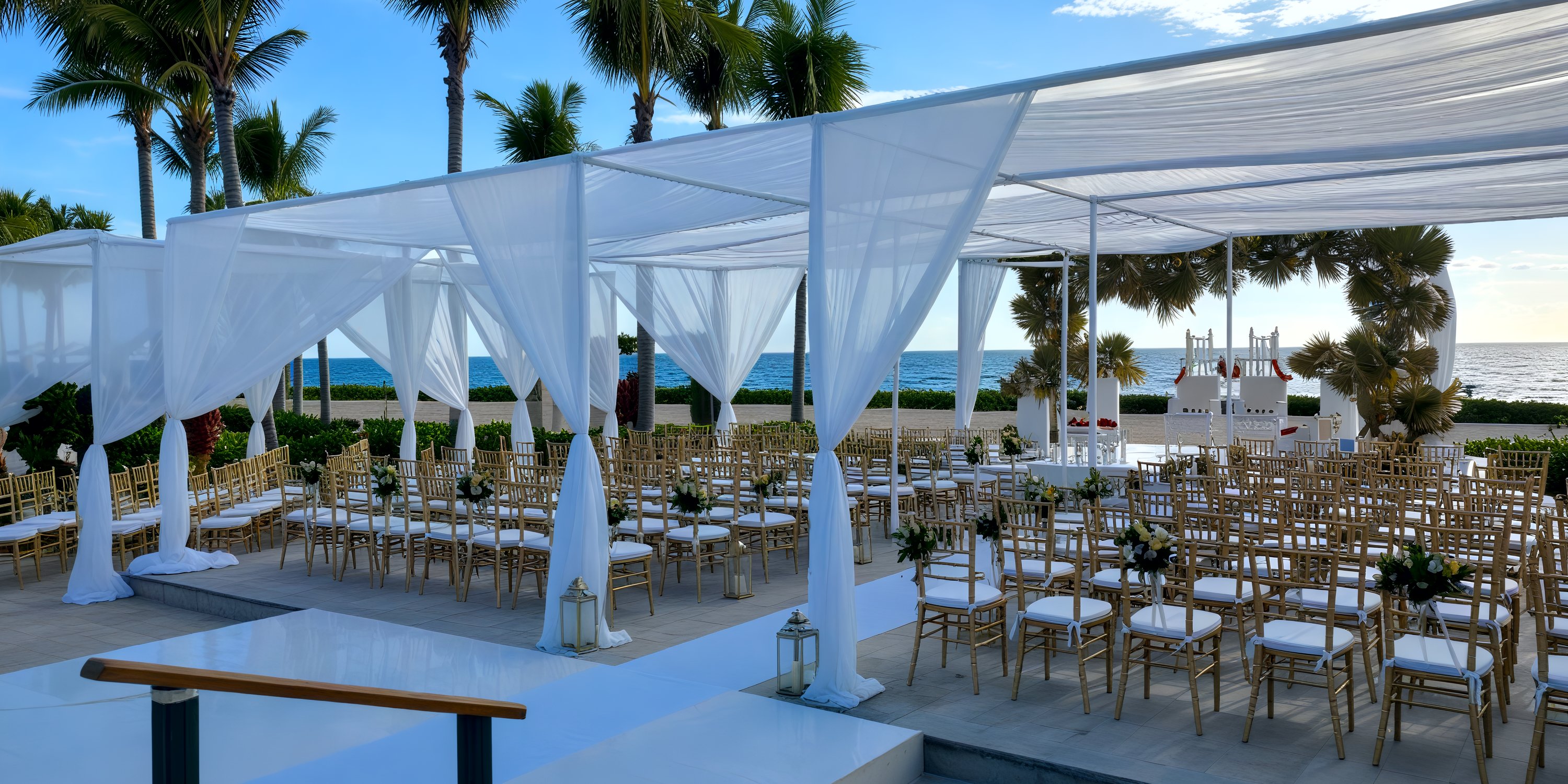 A beautiful destination wedding setup featuring chairs draped in white along the picturesque beachfront.
