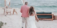 A couple strolls a sandy beach at the Hilton Tulum Riviera Maya, perfect for a romantic destination wedding.