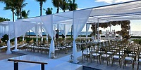 Destination wedding at Hilton Tulum Riviera Maya Resort with white drapery, gold chairs, and ocean view.