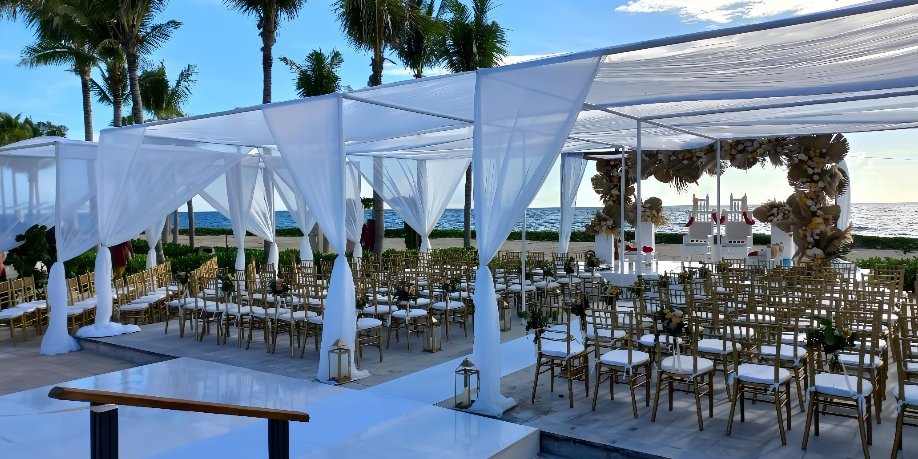Destination wedding at Hilton Tulum Riviera Maya Resort with white drapery, gold chairs, and ocean view.