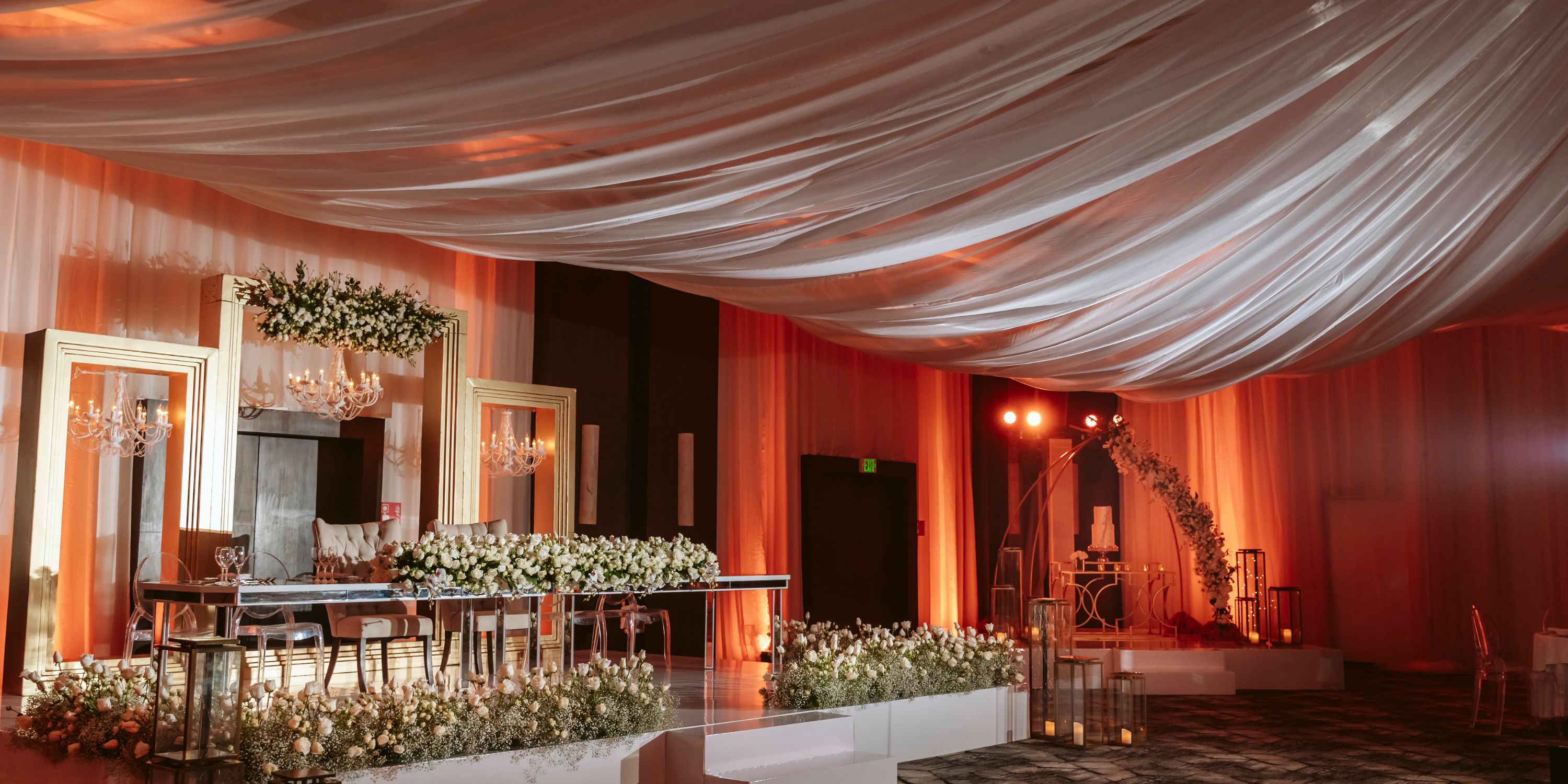 Le Blanc Spa Resort Cancun hall styled for a destination wedding with draped ceilings, flowers, and tables.