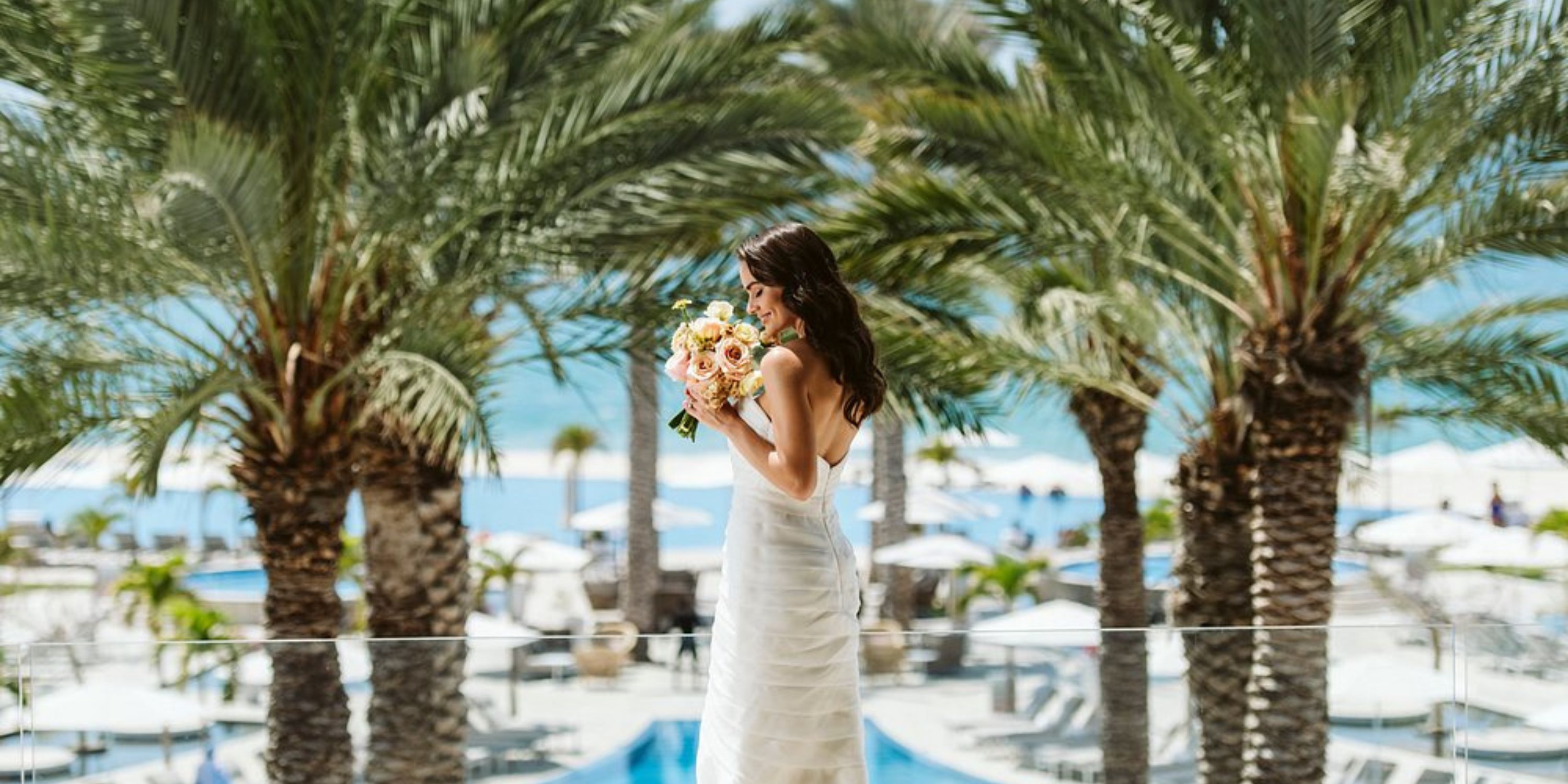 Bride in white dress at destination wedding by pool and ocean at Le Blanc Spa Resort Los Cabos, palms.