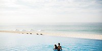 A couple in an infinity pool at Le Blanc Spa Resort Los Cabos, perfect for a destination wedding, overlooks the beach and ocean.