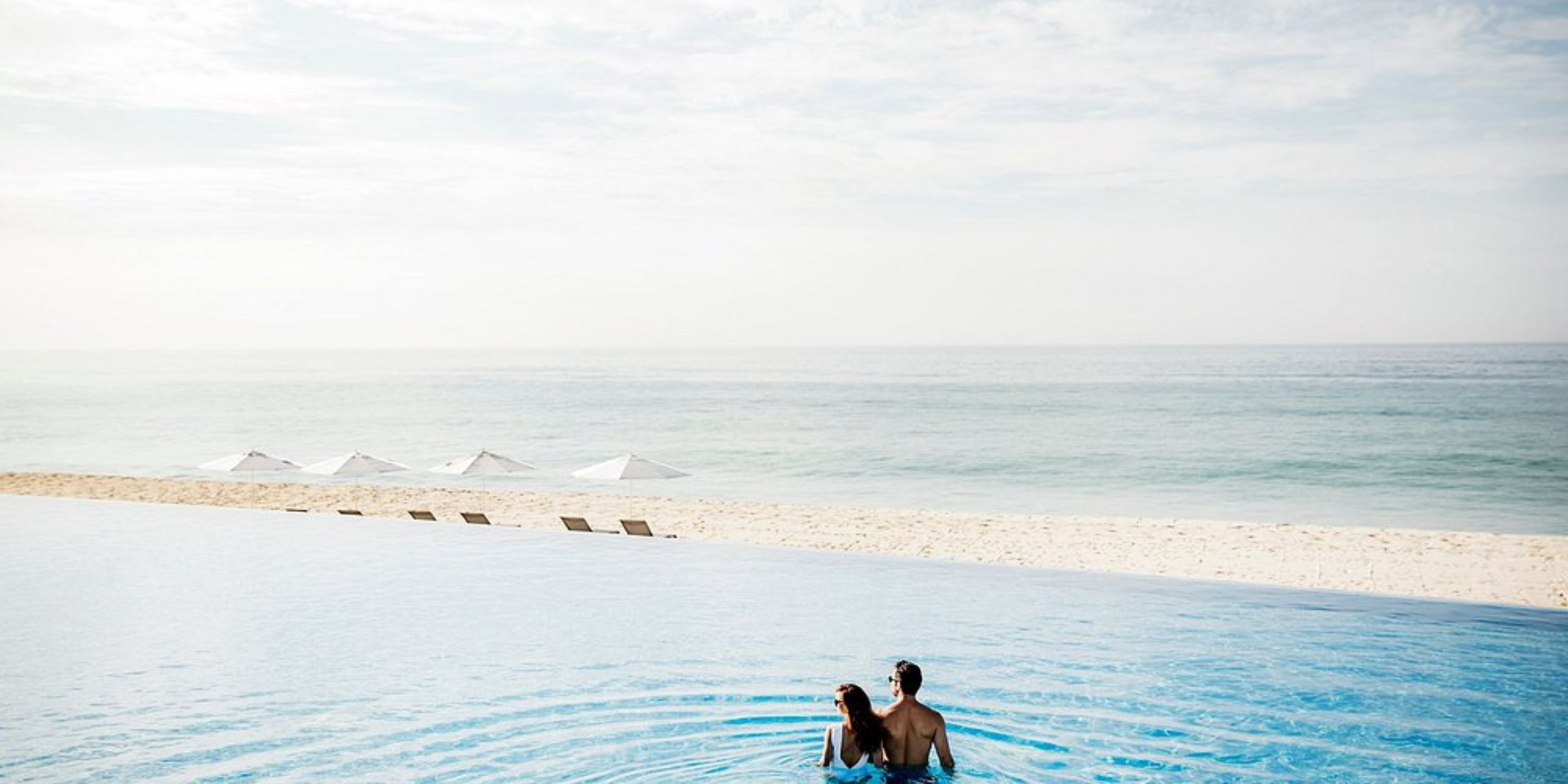 A couple in an infinity pool at Le Blanc Spa Resort Los Cabos, perfect for a destination wedding, overlooks the beach and ocean.