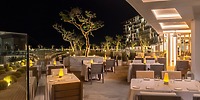 Le Blanc Spa Resort Los Cabos patio at night, ideal for a destination wedding, with lit trees and empty tables.