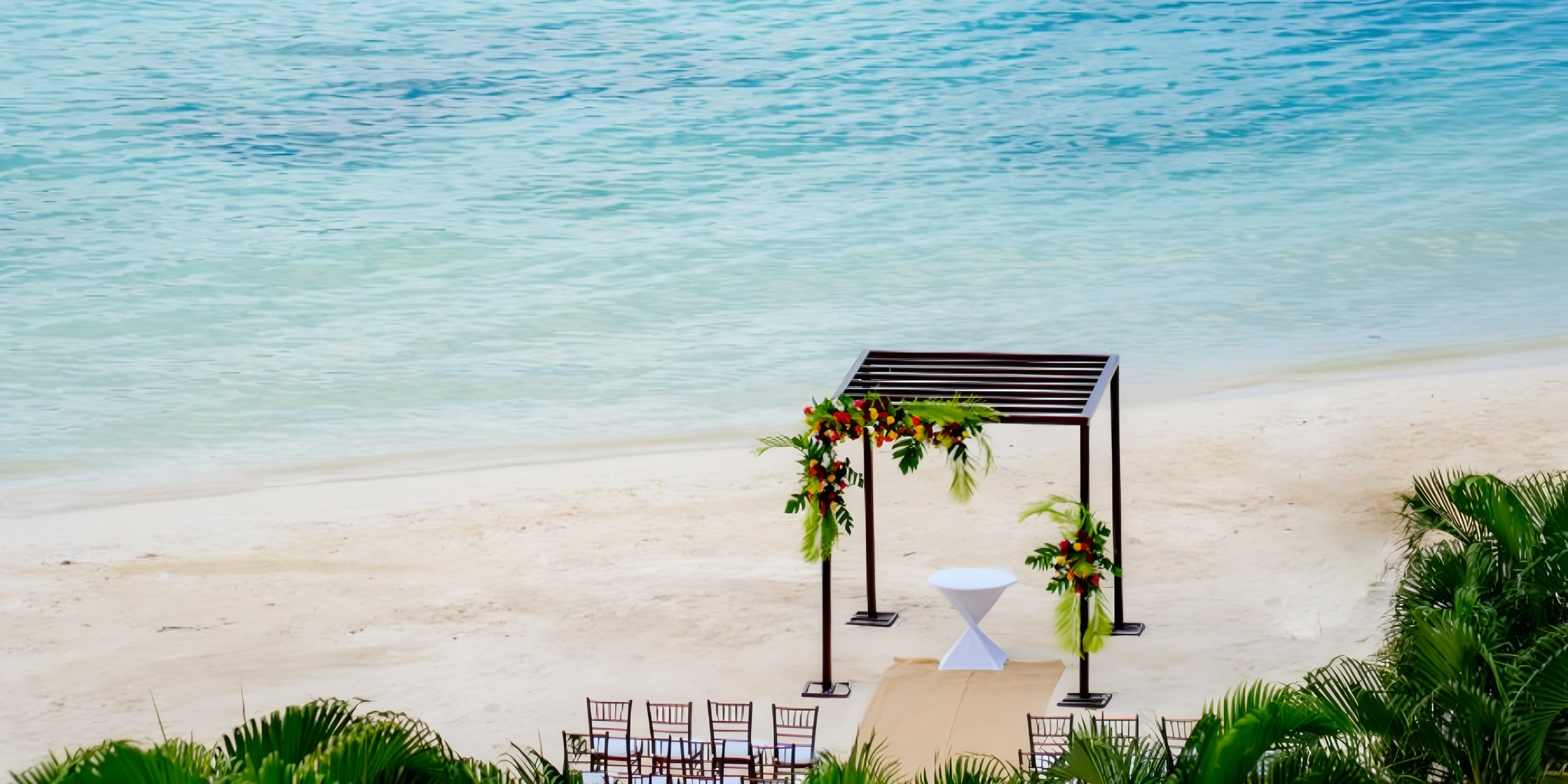 Beachfront destination wedding arch with chairs and elegant decor at Moon Palace Jamaica.