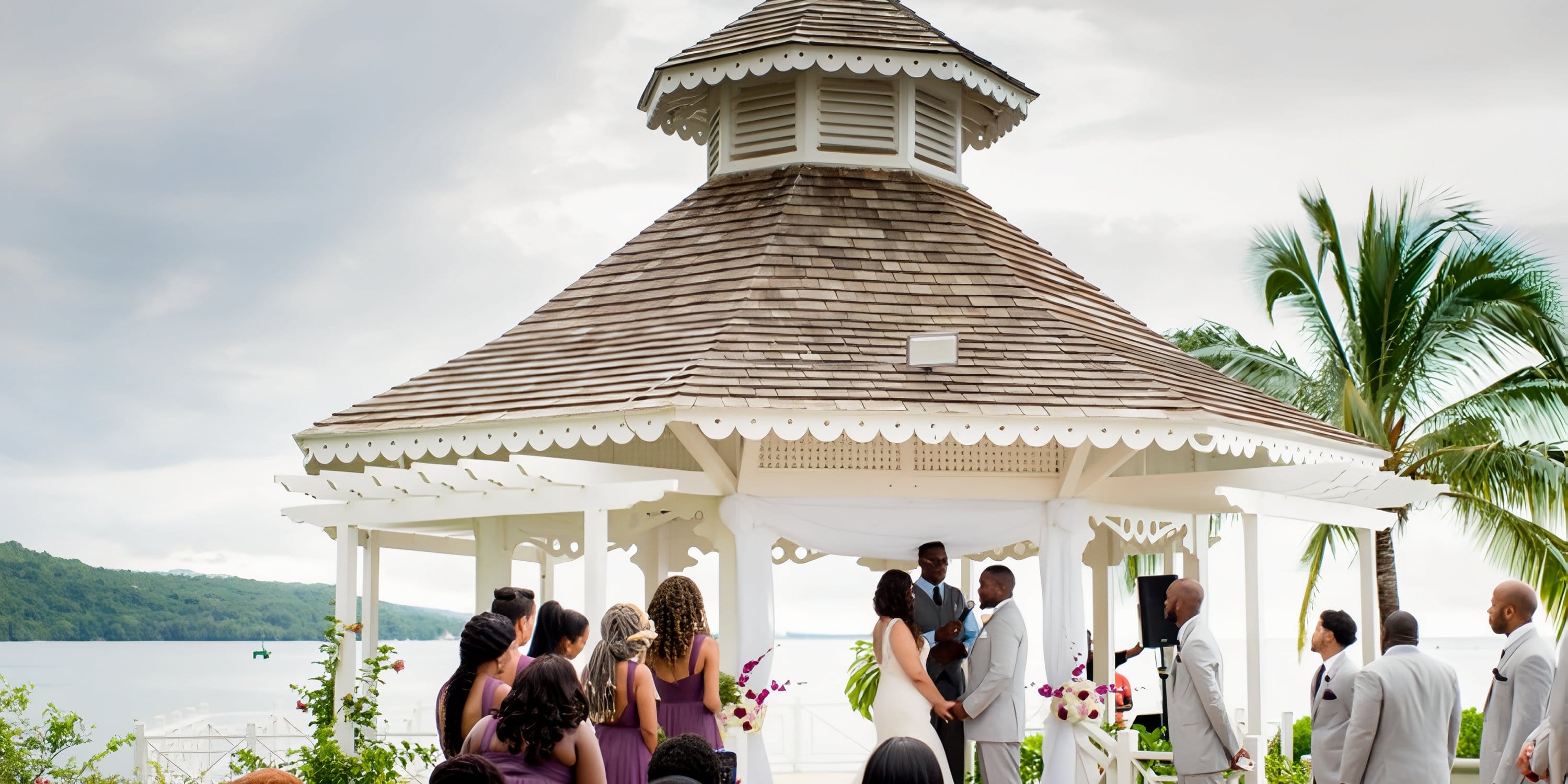 A destination wedding at Moon Palace Jamaica beneath a gazebo by the ocean, guests in attendance.