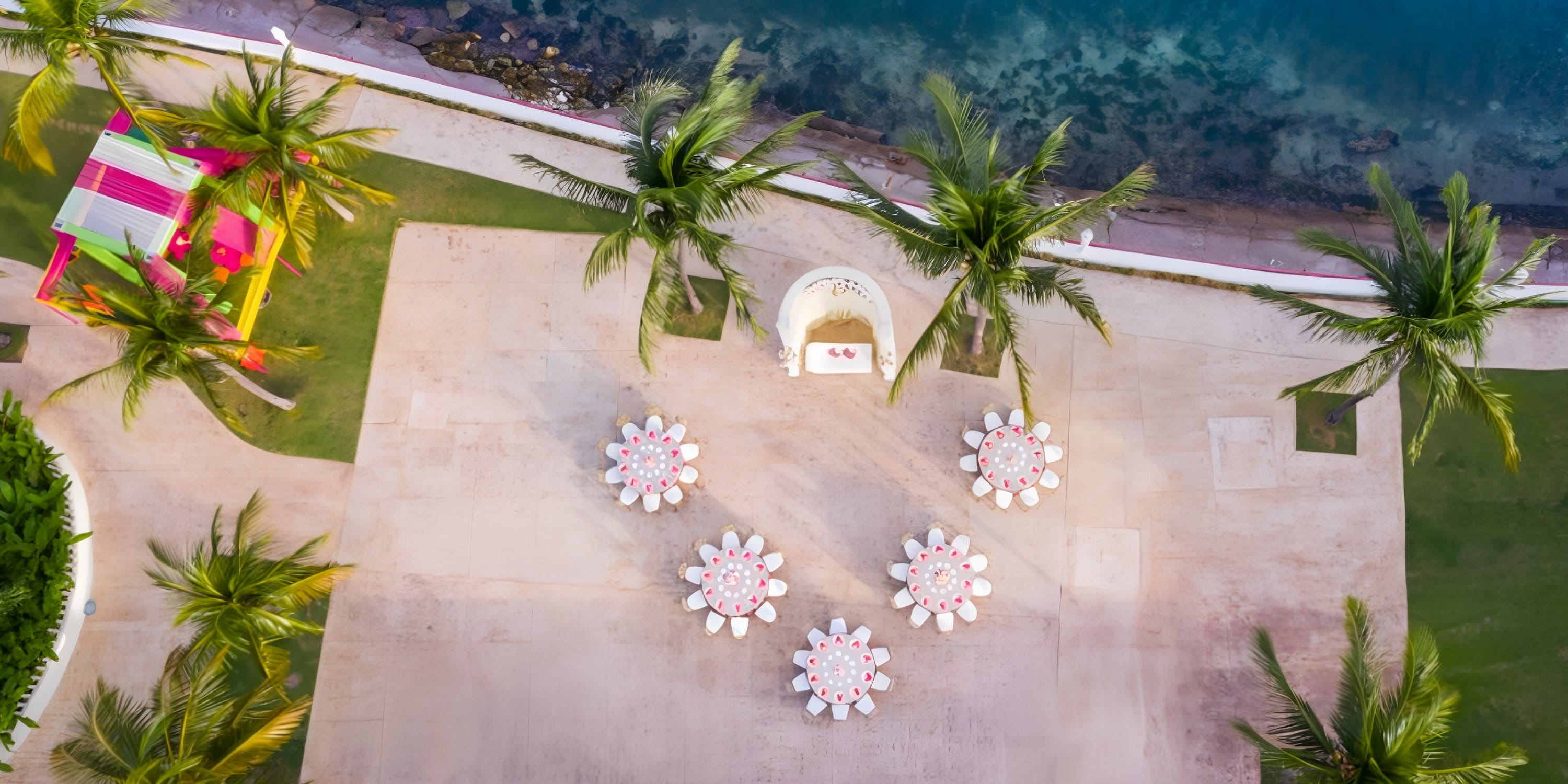 Aerial view of destination wedding tables and palm trees on Moon Palace Jamaica’s waterfront patio.