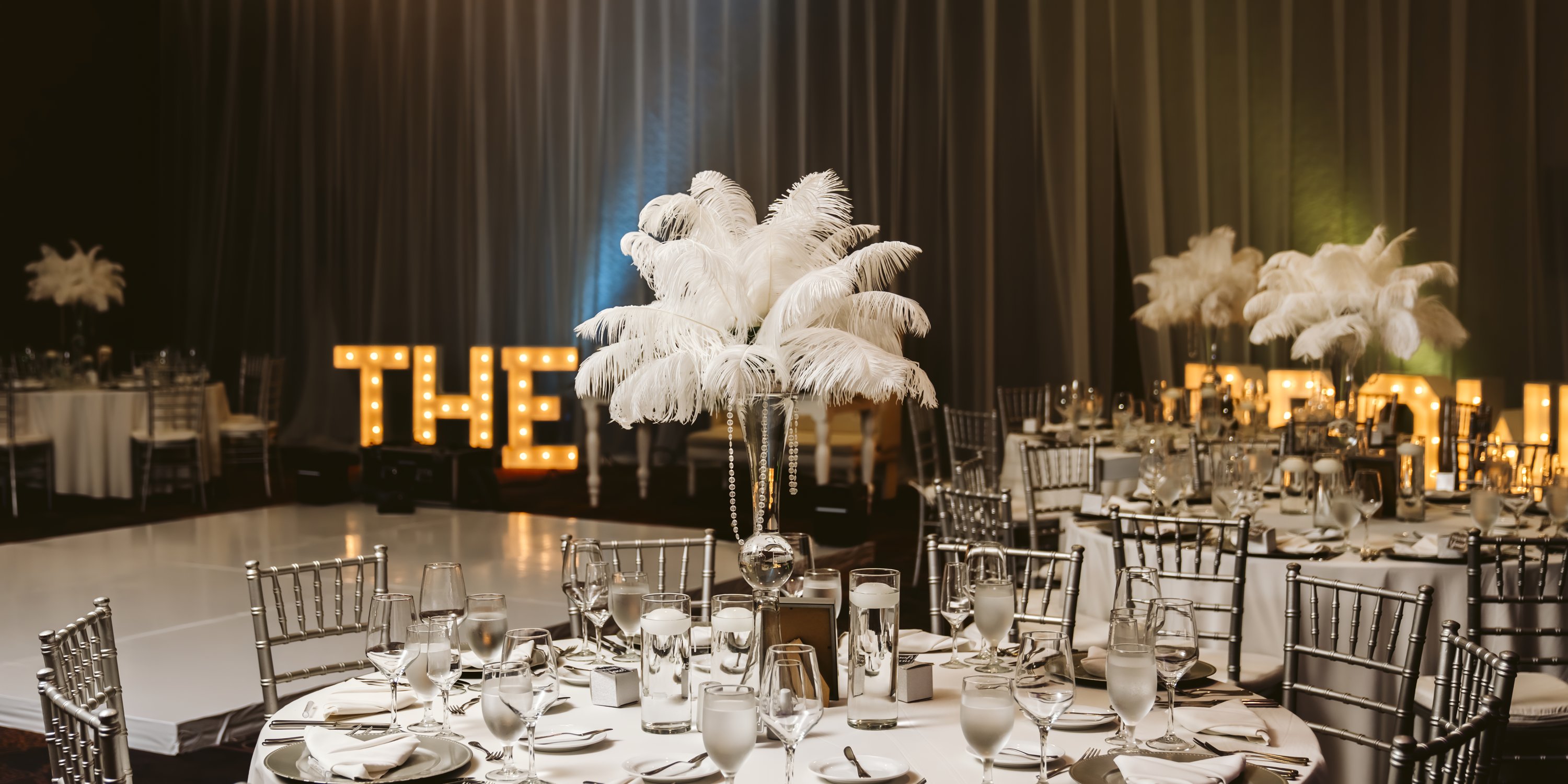 Elegant destination wedding tables at Moon Palace Jamaica, white feather centerpieces, "THE PROM" lights.