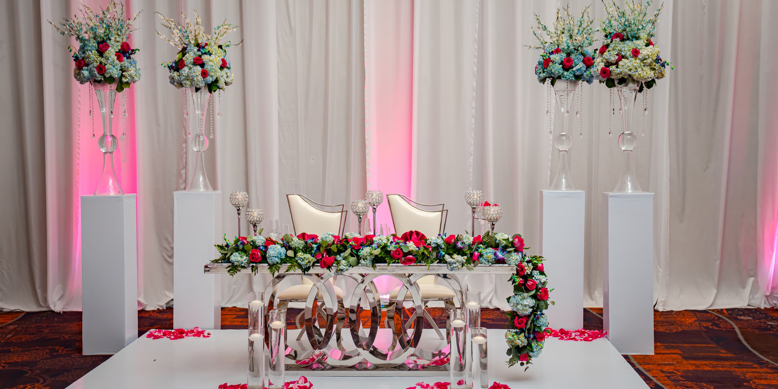 Wedding sweetheart table at Moon Palace Jamaica with two chairs, flowers, and rose petals for a destination wedding.