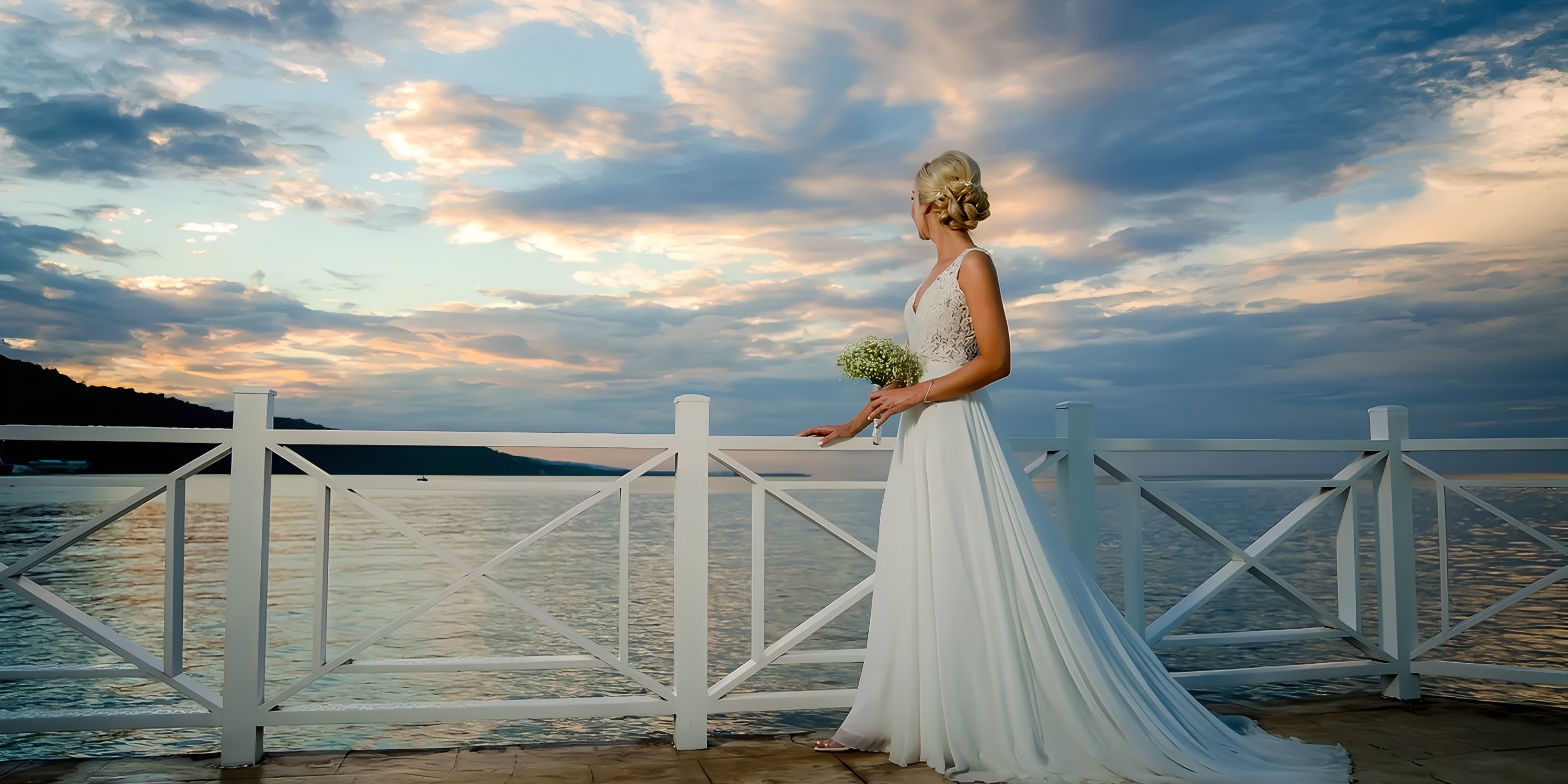 A bride in a white wedding dress stands by the waterfront at Moon Palace Jamaica during sunset, showcasing a destination wedding.