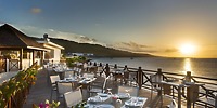 Set tables for a destination wedding on Moon Palace Jamaica&rsquo;s outdoor patio overlook the ocean at sunset.