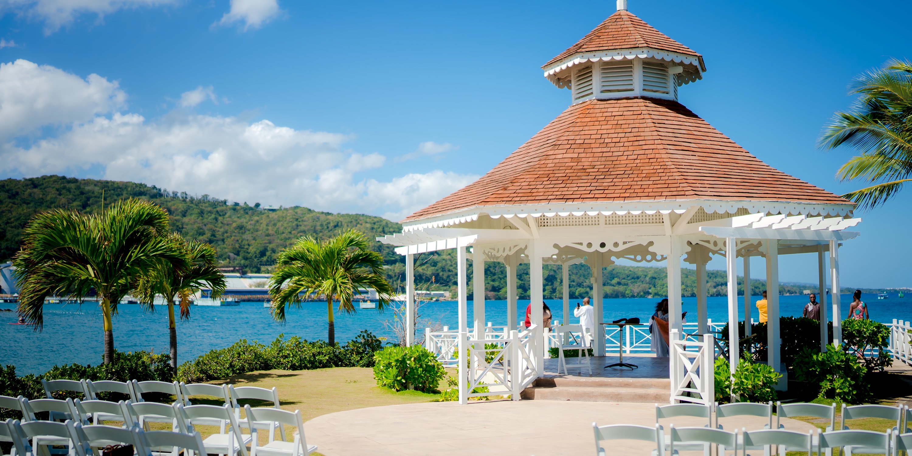 White gazebo at Moon Palace Jamaica set for a destination wedding, with chairs, palm trees, and mountain views.