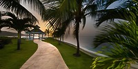Curved path with palm trees leads to a gazebo by the ocean, perfect for a destination wedding at Moon Palace Jamaica.