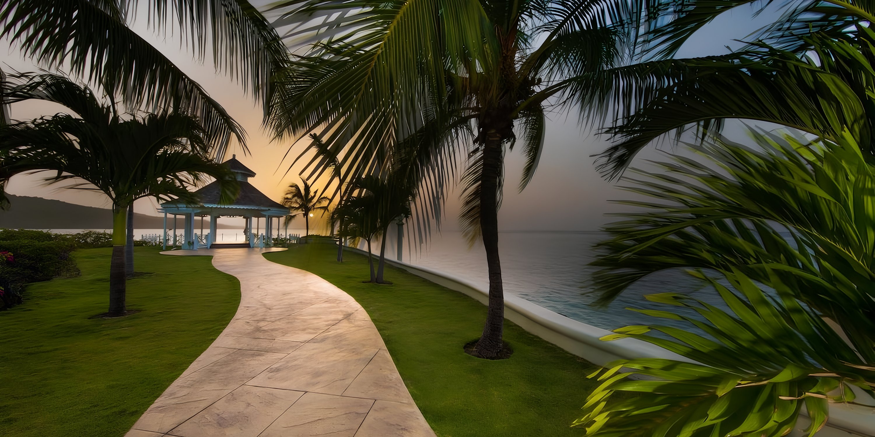 Curved path with palm trees leads to a gazebo by the ocean, perfect for a destination wedding at Moon Palace Jamaica.