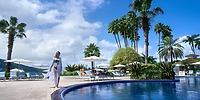 Woman in swimwear by the pool at Moon Palace Jamaica, a popular destination wedding spot with loungers, umbrellas, and palm trees.