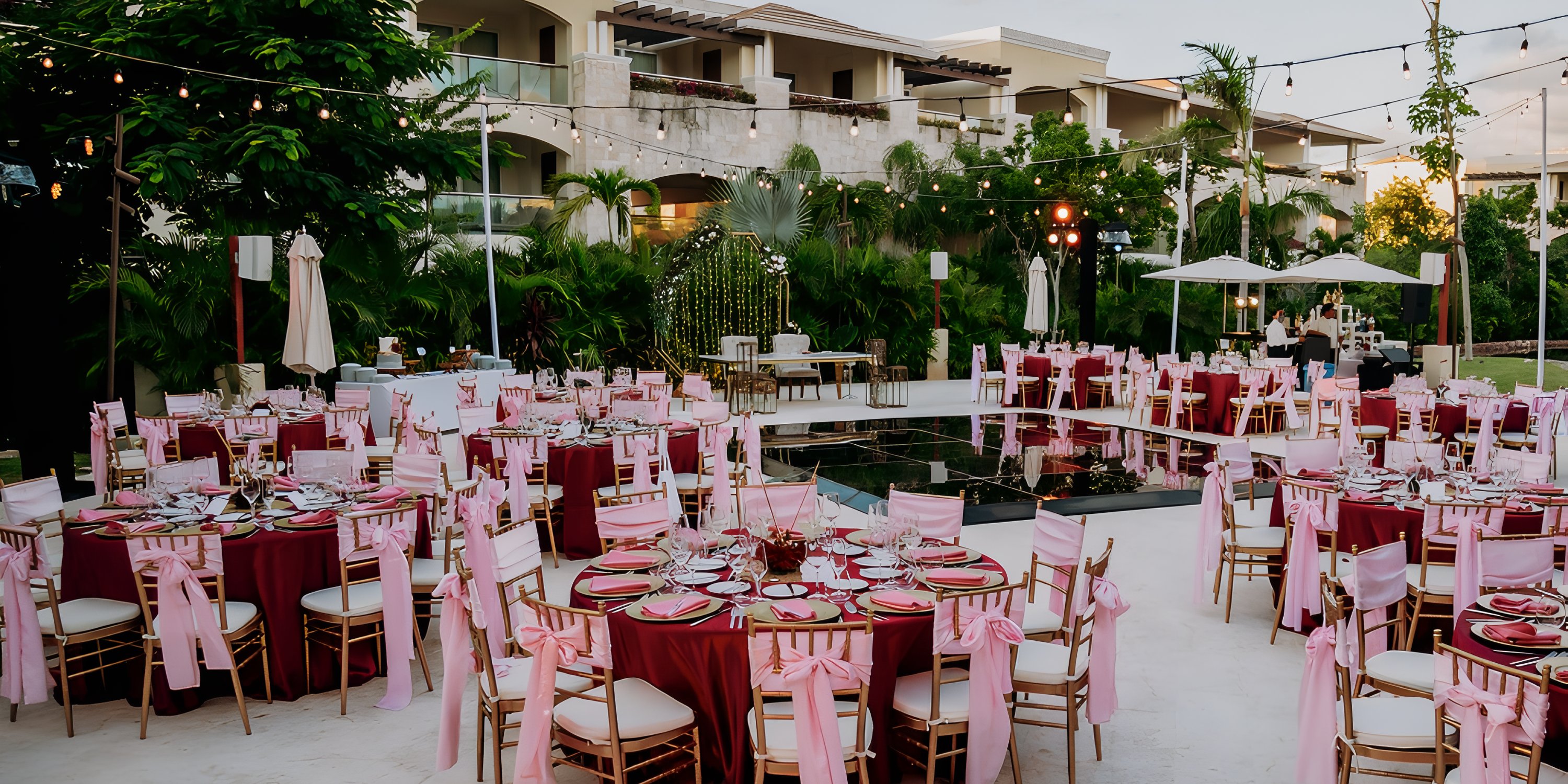 Outdoor destination wedding at Moon Palace The Grand with round tables, pink decor, and string lights.