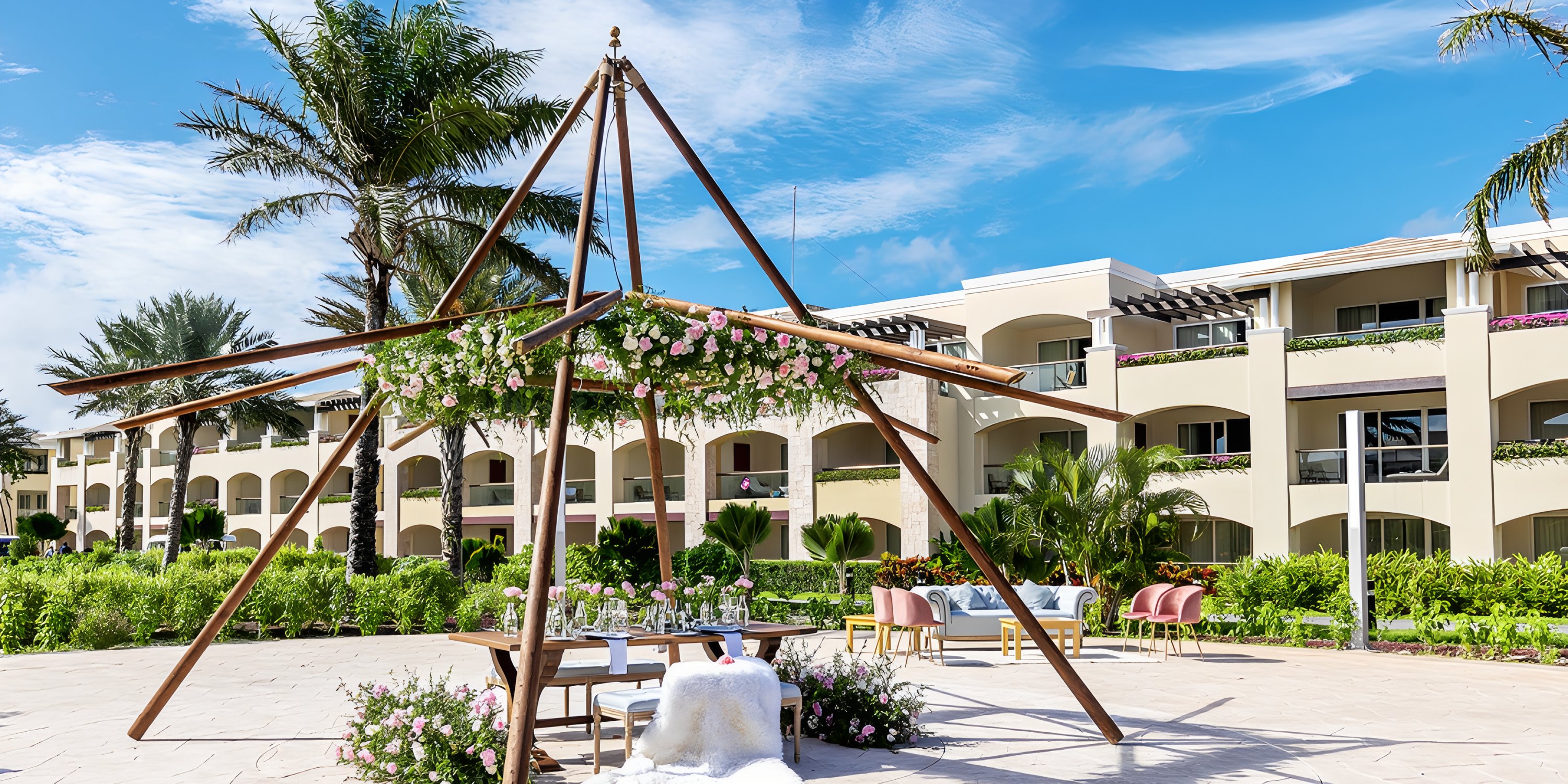 Destination wedding setup featuring a floral arch, table, and chairs at Moon Palace The Grand resort outdoors.