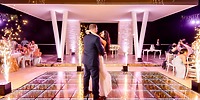 A couple dances on a illuminated floor with sparklers, as guests seated nearby at Moon Palace The Grand celebrate their destination wedding.