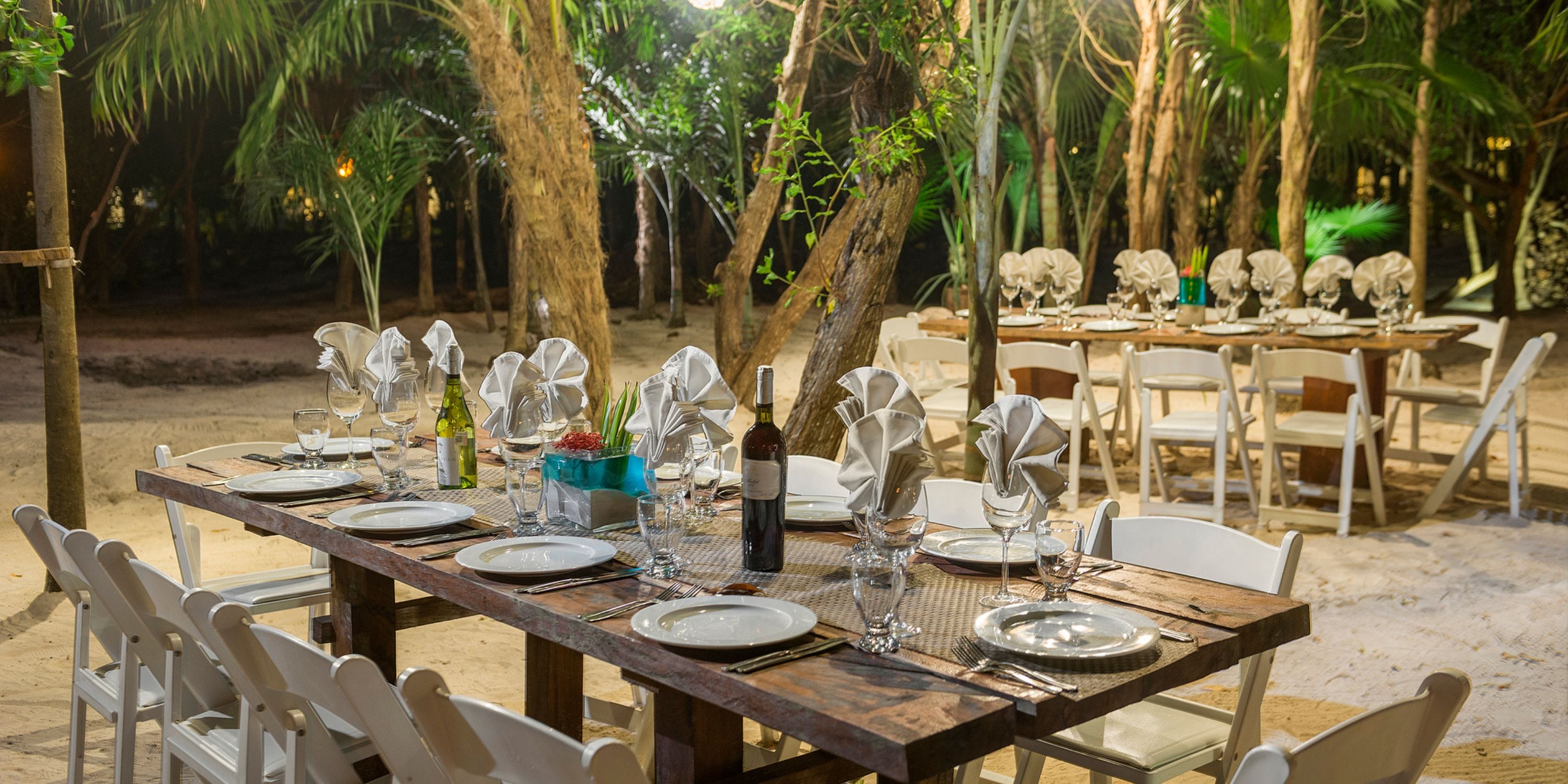 Outdoor dining set at Ocean Coral and Turquesa, set for a destination wedding dinner at night.