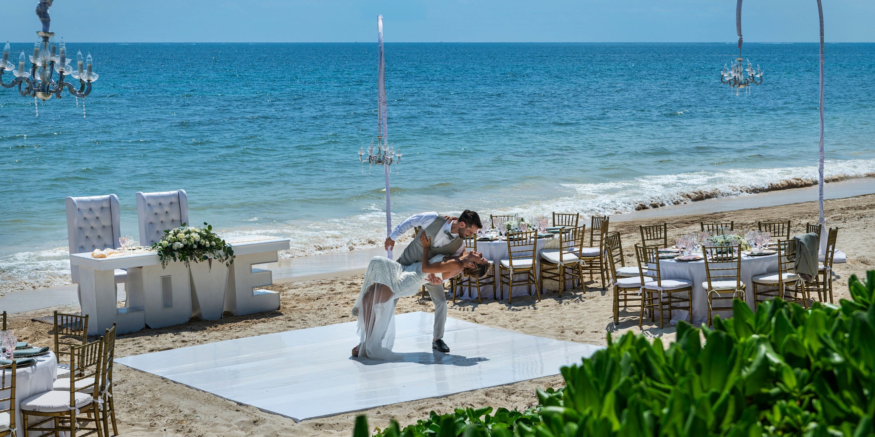 A couple shares a dance on a white platform at their Ocean Coral and Turquesa destination wedding.