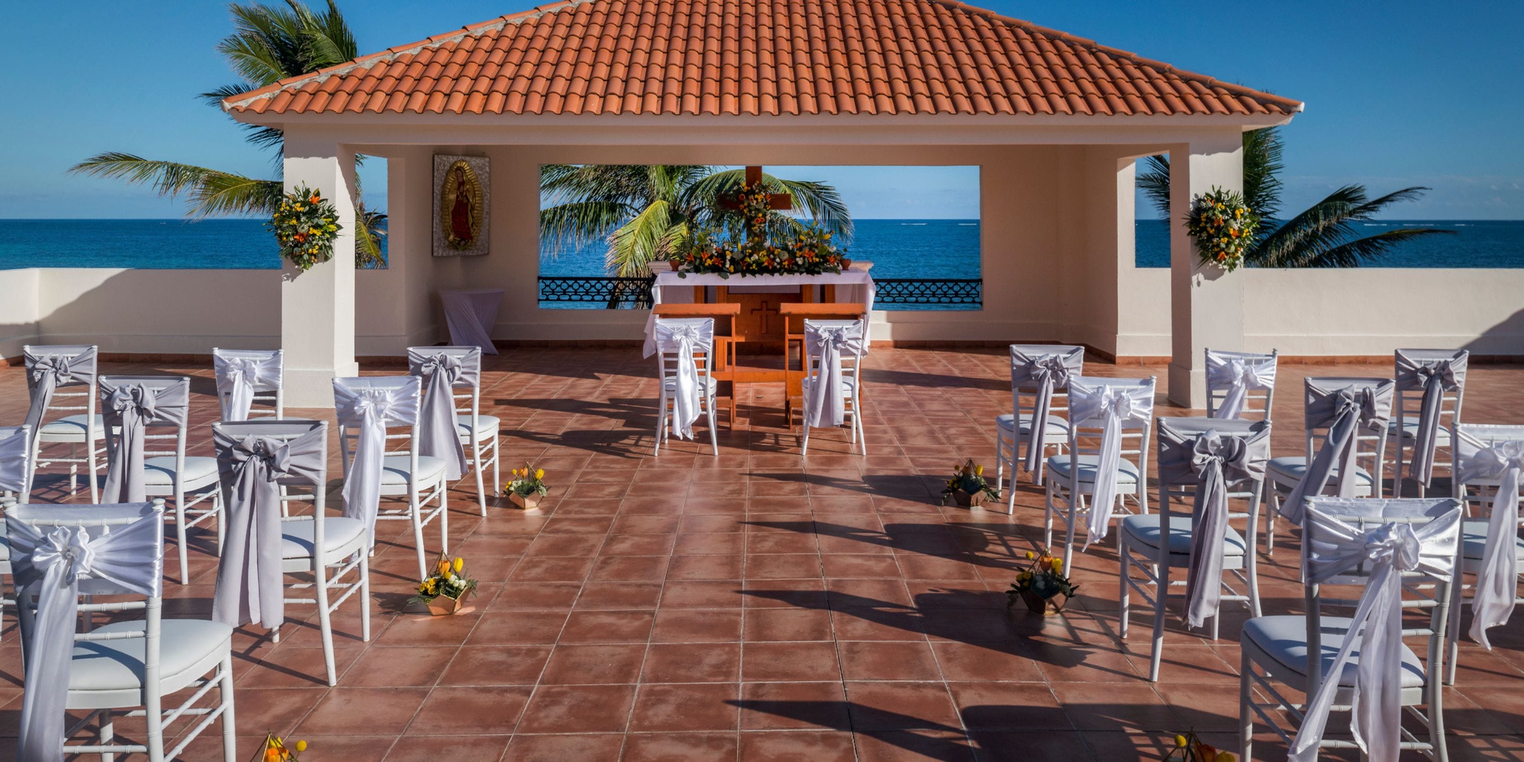 Destination wedding ceremony with rows of white chairs and floral accents overlooking the ocean.