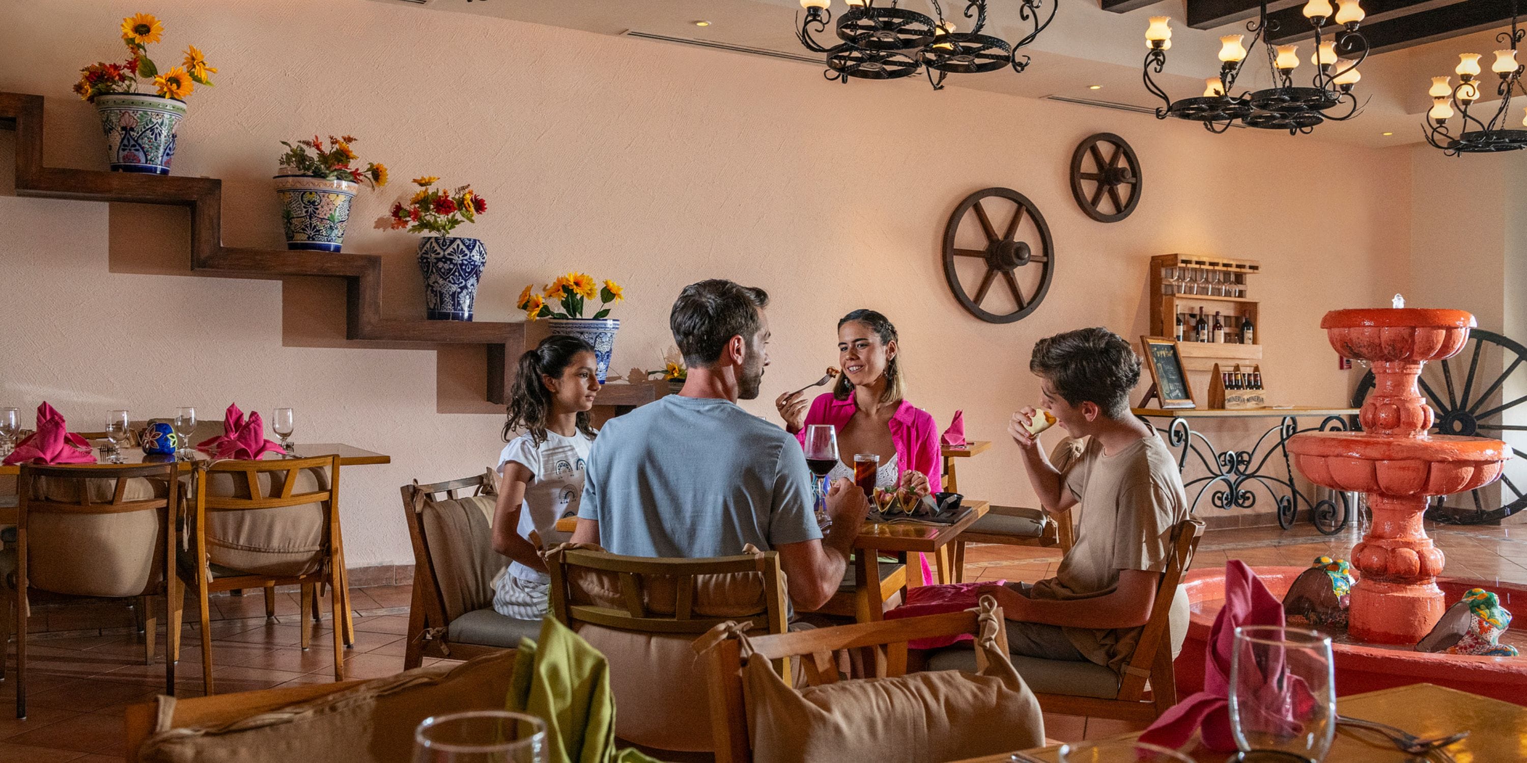 Four guests enjoy dinner and conversation at Ocean Coral and Turquesa, a popular destination wedding spot.