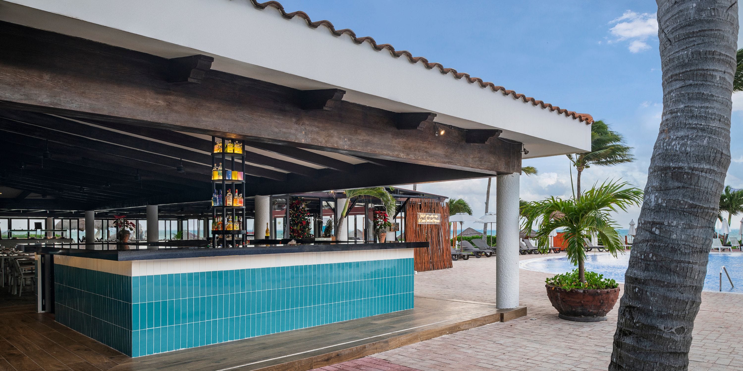 Blue-tiled outdoor bar by the pool with palms and lounge chairs, perfect for a destination wedding.