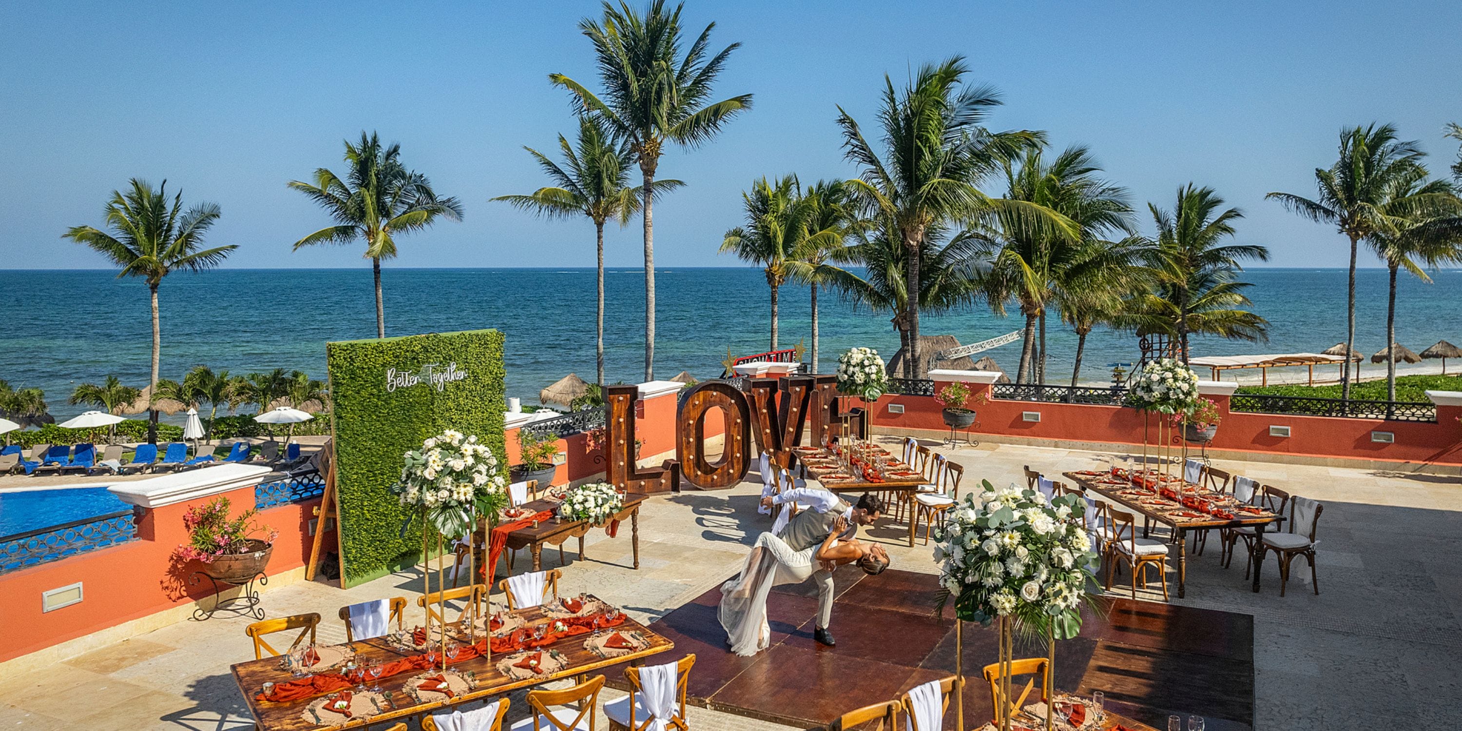 Destination wedding at Ocean Coral and Turquesa with ocean view, palm trees, dining tables, and "LOVE" letters.