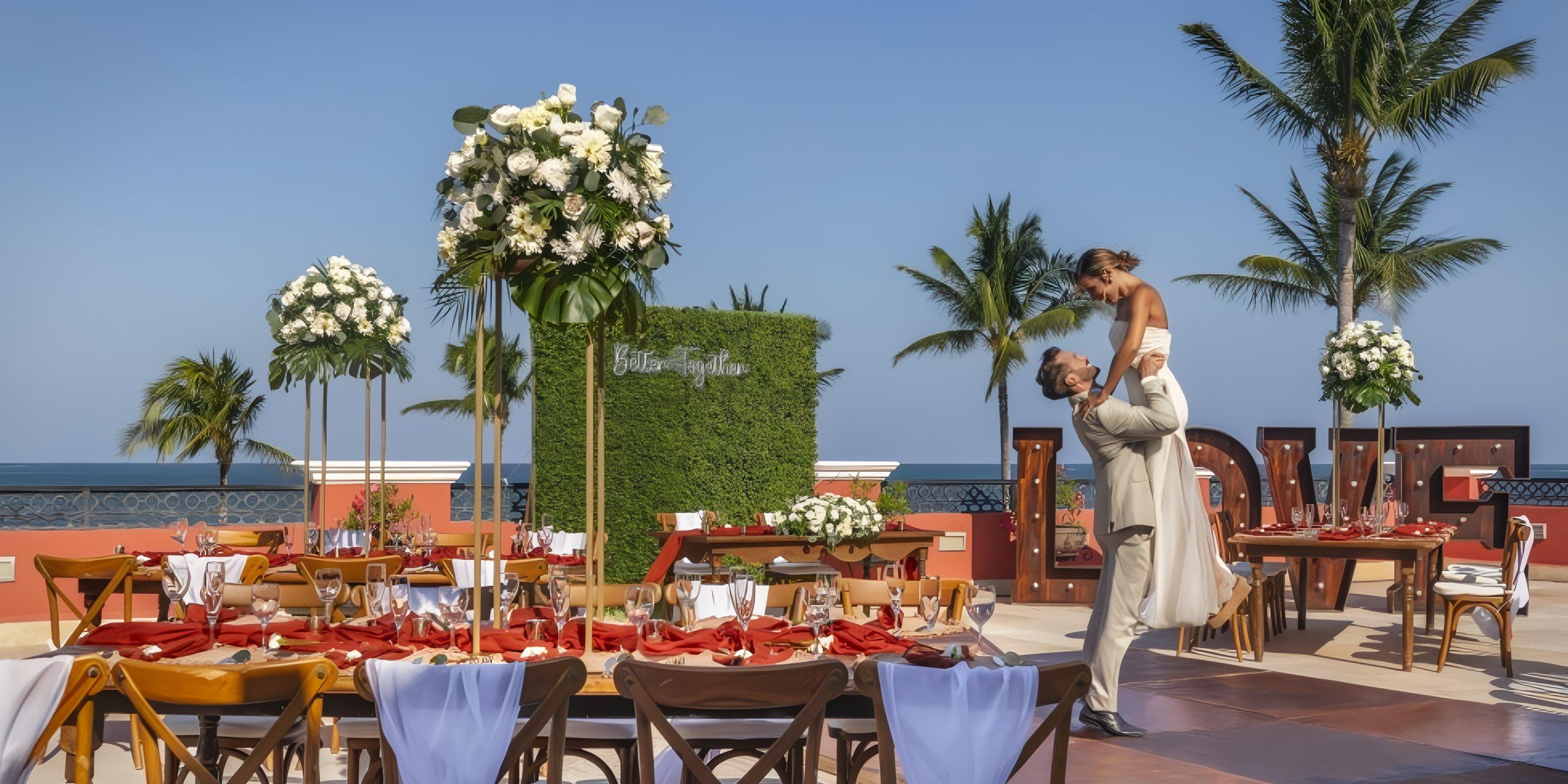 Newlyweds celebrate their destination wedding at Ocean Coral and Turquesa among decorated tables and palms.