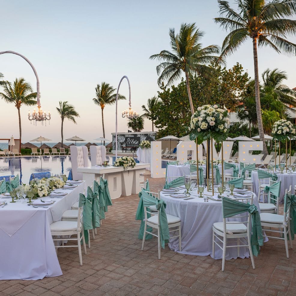Elegant destination wedding reception outdoors, featuring white tables, floral centerpieces, and LOVE letters.