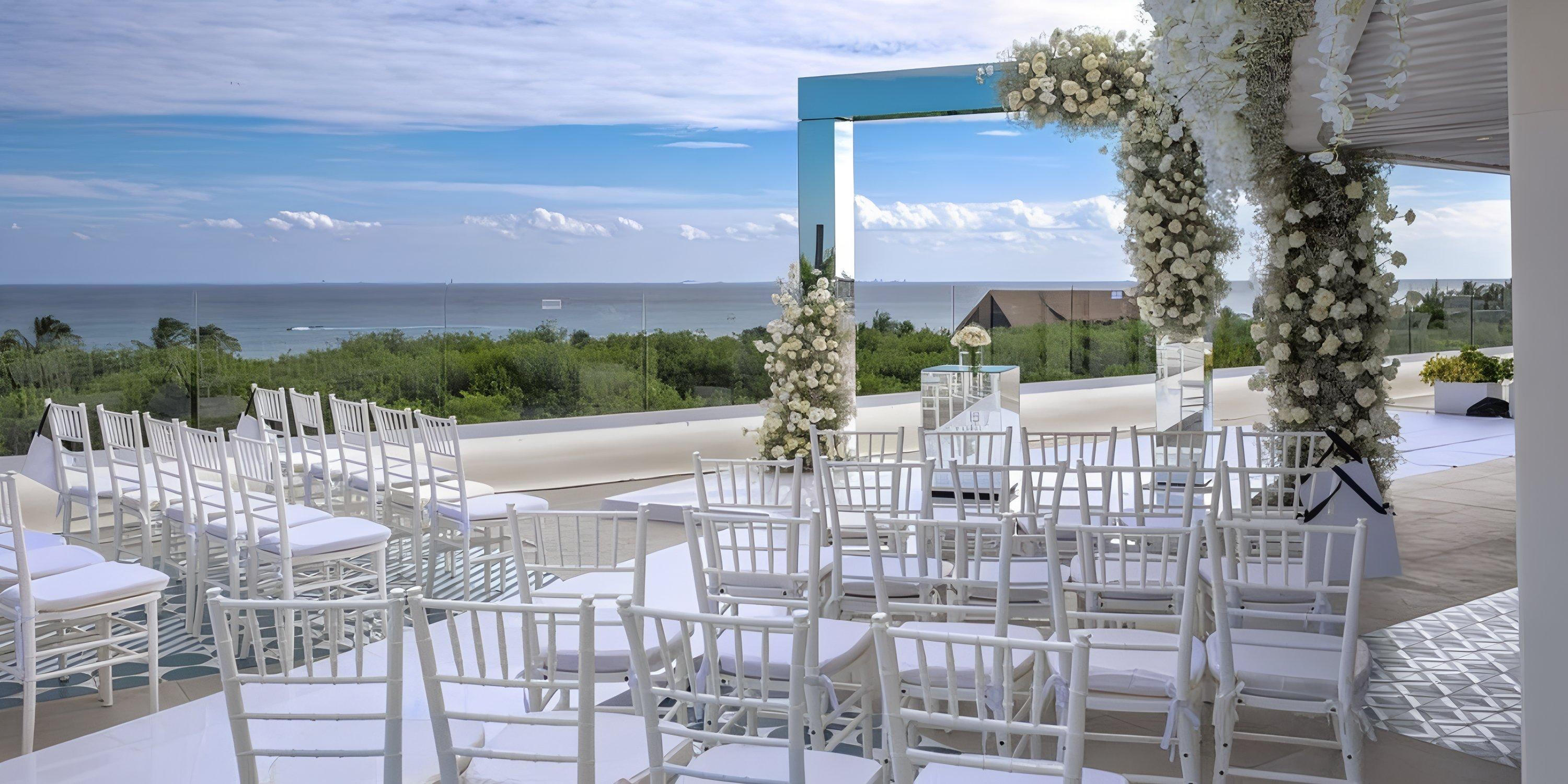 White chairs and a floral arch arranged at Ocean Riviera Paradise for a beautiful destination wedding ceremony.
