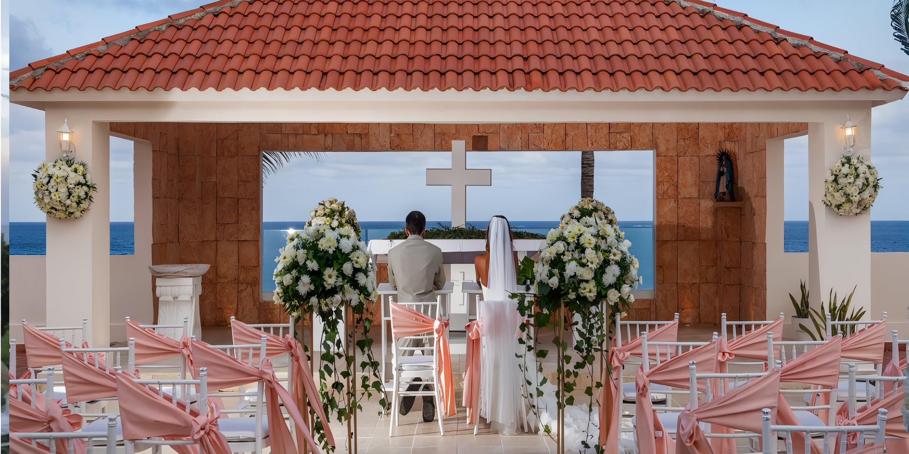 Couple at Ocean Coral and Turquesa wedding altar, facing the ocean at their destination wedding ceremony.
