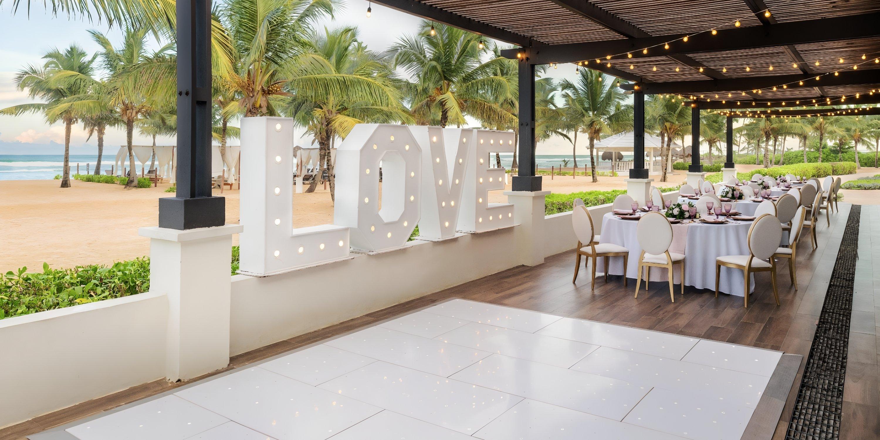 Ocean El Faro: Destination wedding venue with LOVE sign, round tables, and stunning beach backdrop.