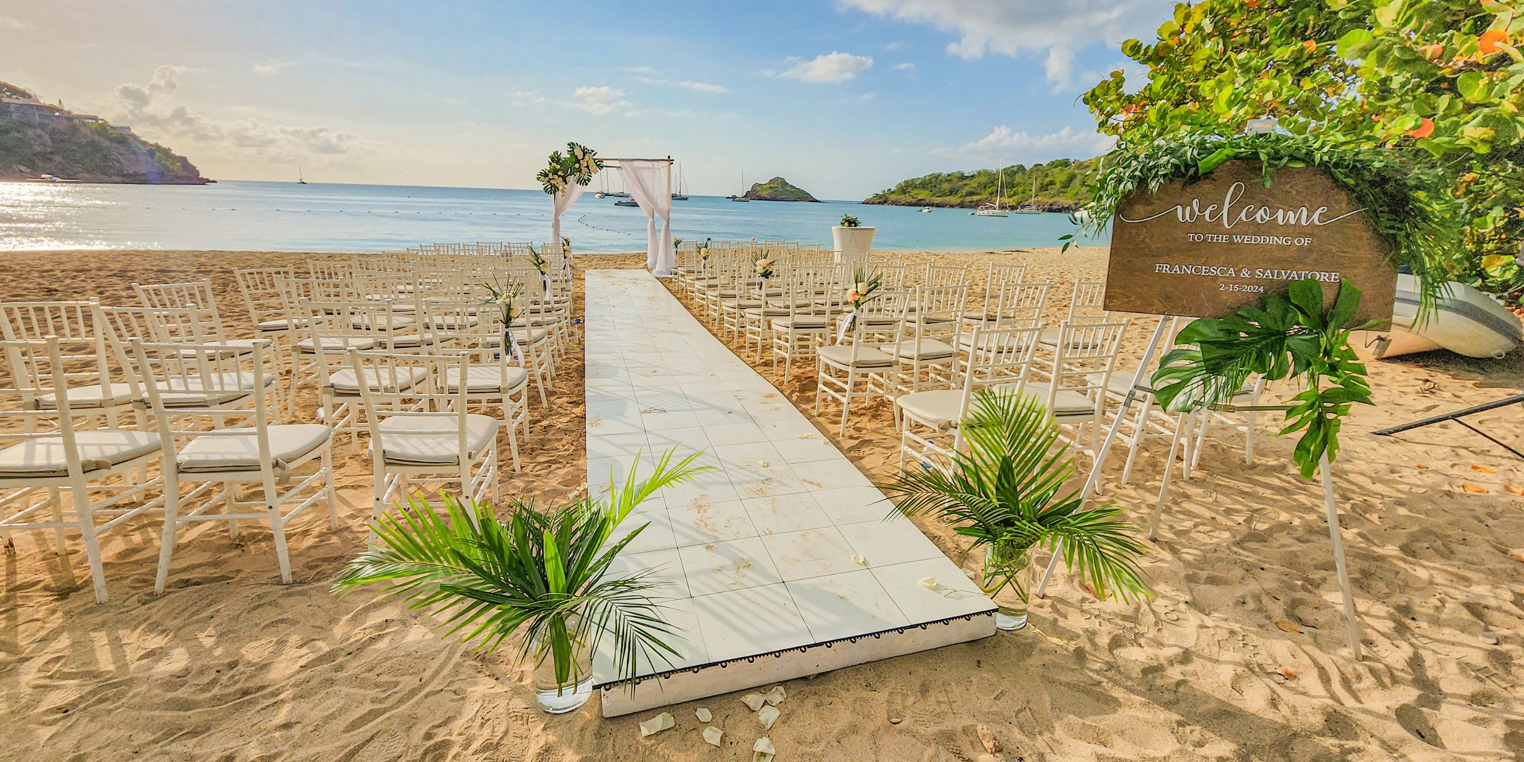 Destination wedding setup at Royalton Antigua with white aisle, chairs, welcome sign, and ocean backdrop.