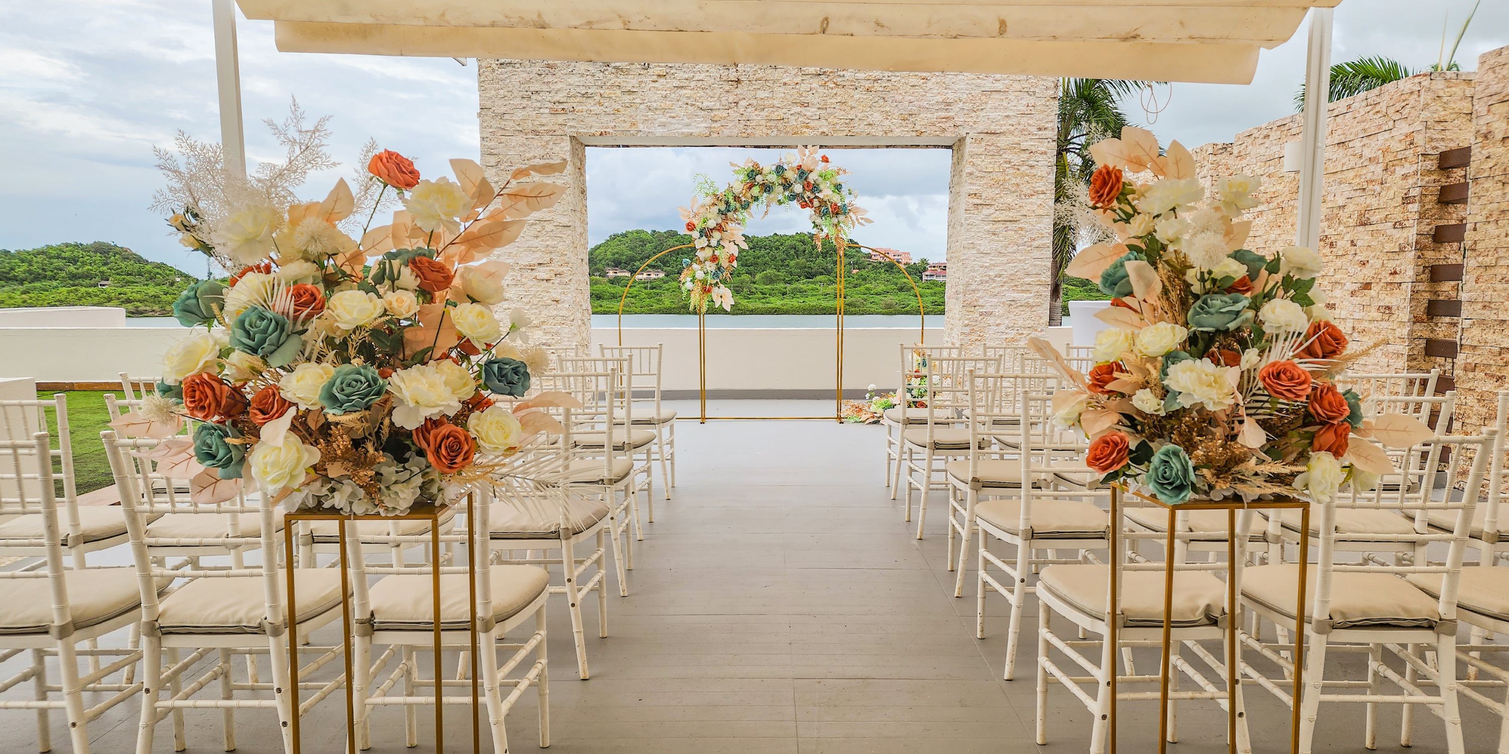 Destination wedding at Royalton Antigua, with white chairs and florals facing the elegant ceremony arch.