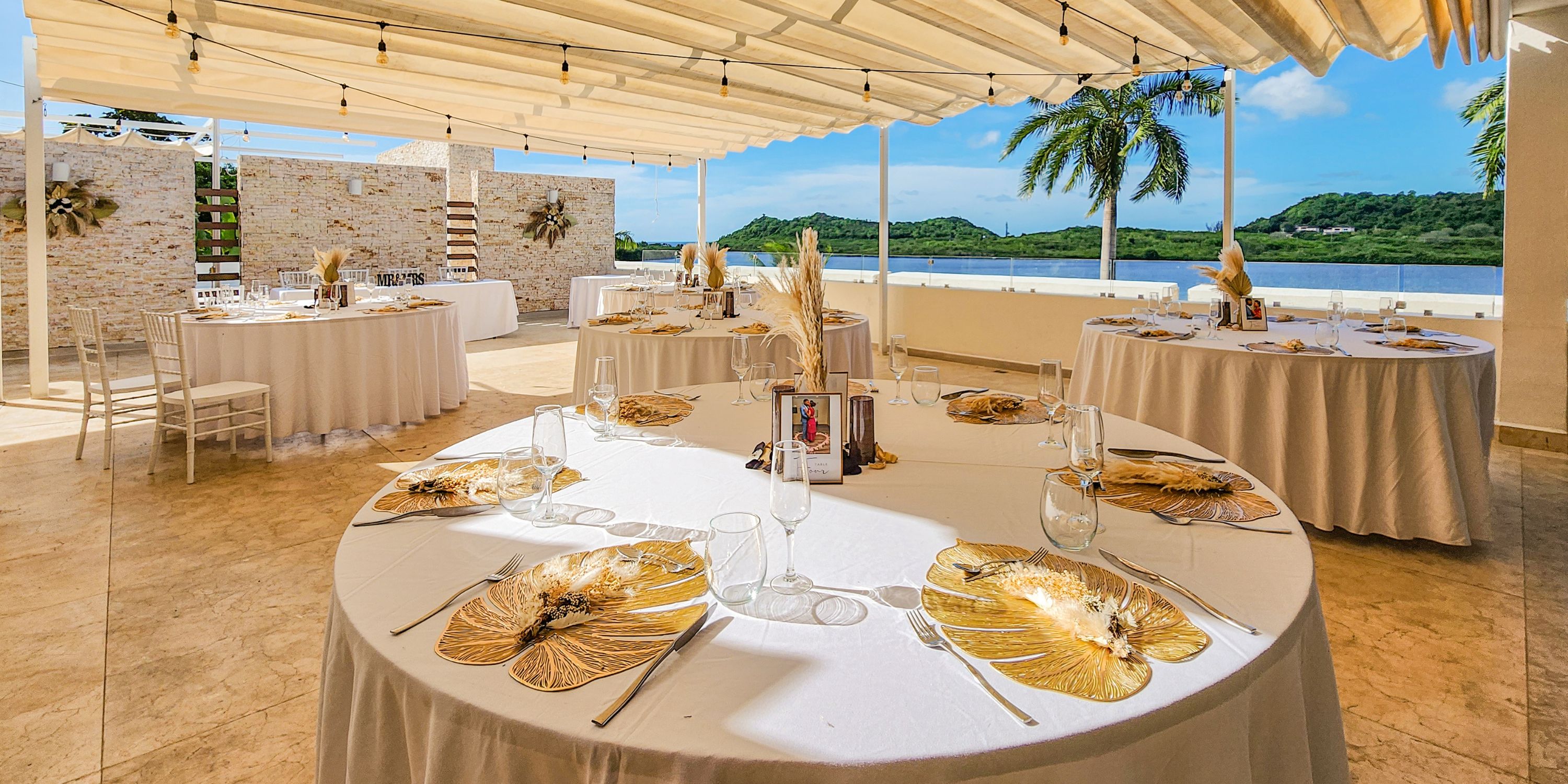 Destination wedding setup at Royalton Antigua with round tables, gold leaf placemats, and water views.